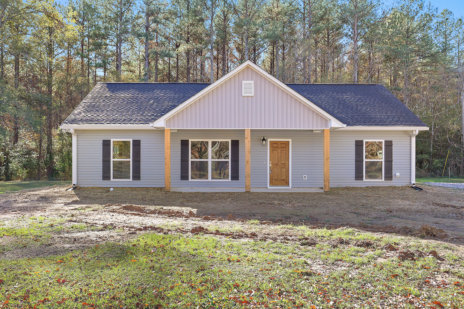 White siding house with covered front porch, wooden door, adjacent windows reflecting nearby trees, landscaped yard, and Little White House visible in the background.