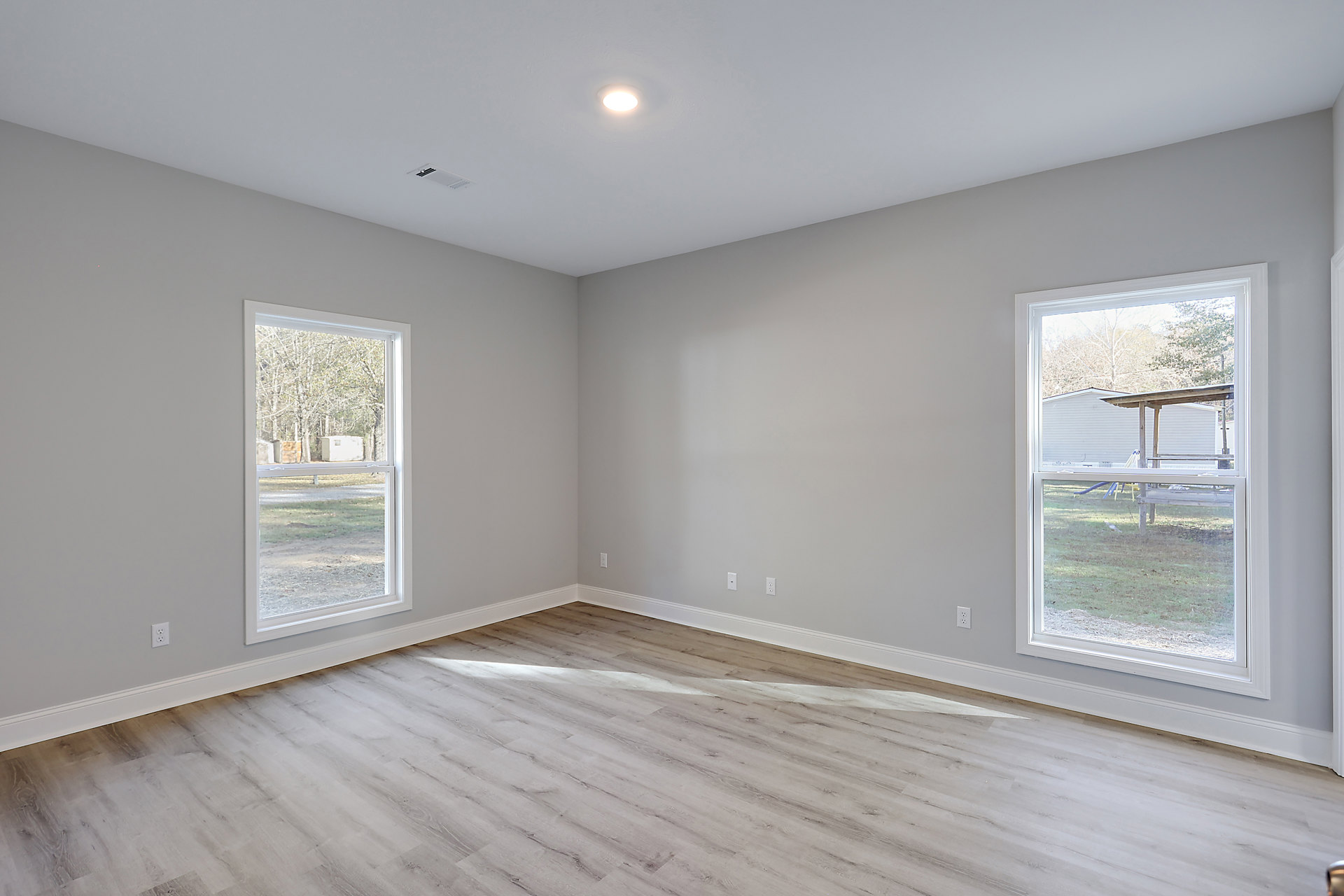 Hardwood floor room with large windows, ceiling light fixture, plaster walls, and view of yard with playground