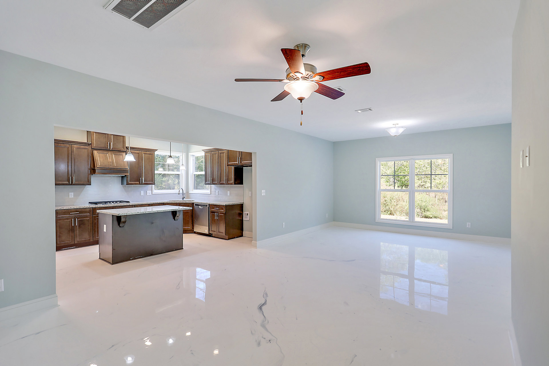 Open kitchen with white cabinetry, black and white marble countertops, ceiling fan with light fixture, large window overlooking trees, white marble tile flooring, and stainless