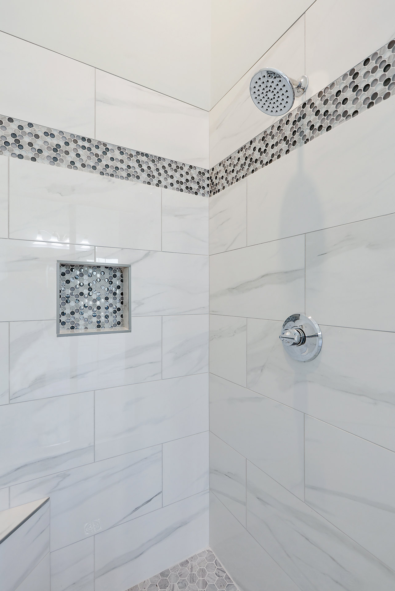 Modern bathroom shower with dual chrome shower heads, circular patterned tile wall, and silver control knob