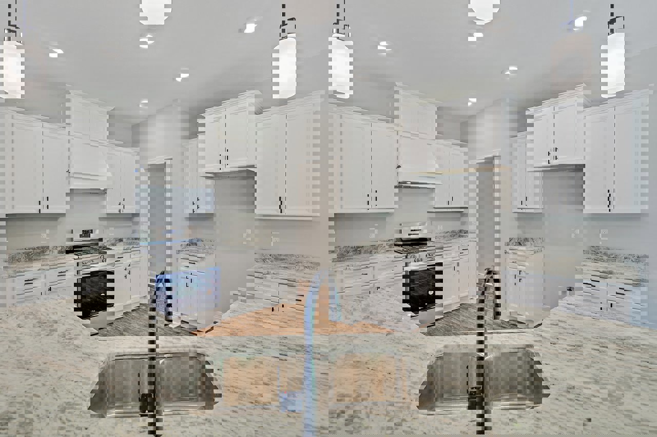 White shaker cabinets, stainless steel sink with chrome faucet, stone countertop, built-in stove and oven, microwave, neutral backsplash