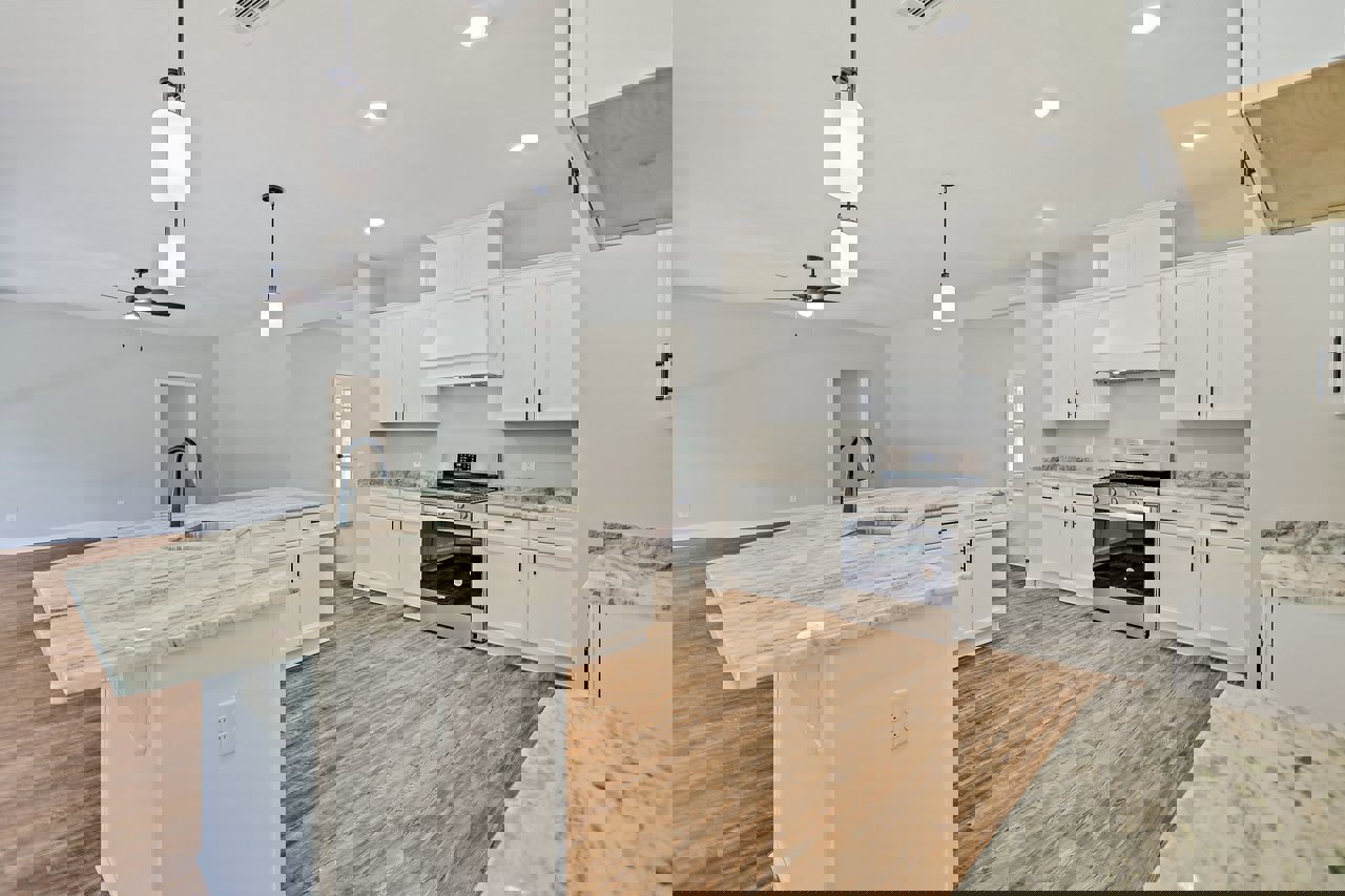 Marble countertops with undermount sink and chrome faucet, wood flooring, white cabinetry, stainless steel stove, and black-edged kitchen island