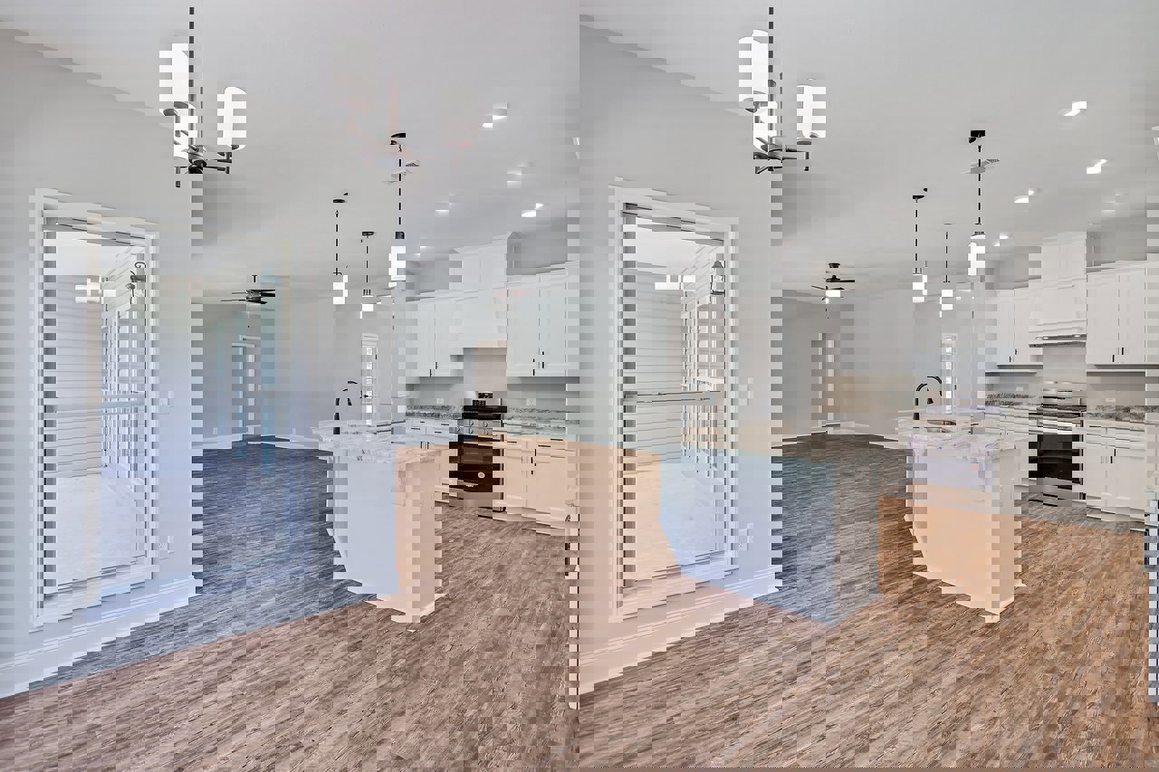 Open-concept kitchen and living room featuring wood flooring, white cabinetry, marble-topped island, stainless steel stove with overhead microwave, and screen door leading outside.