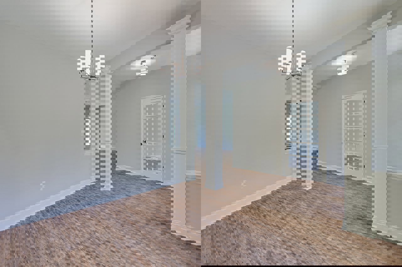 Wood floor room with white pillars, glass-paneled white door, four-light chandelier, white walls, and blue trim.