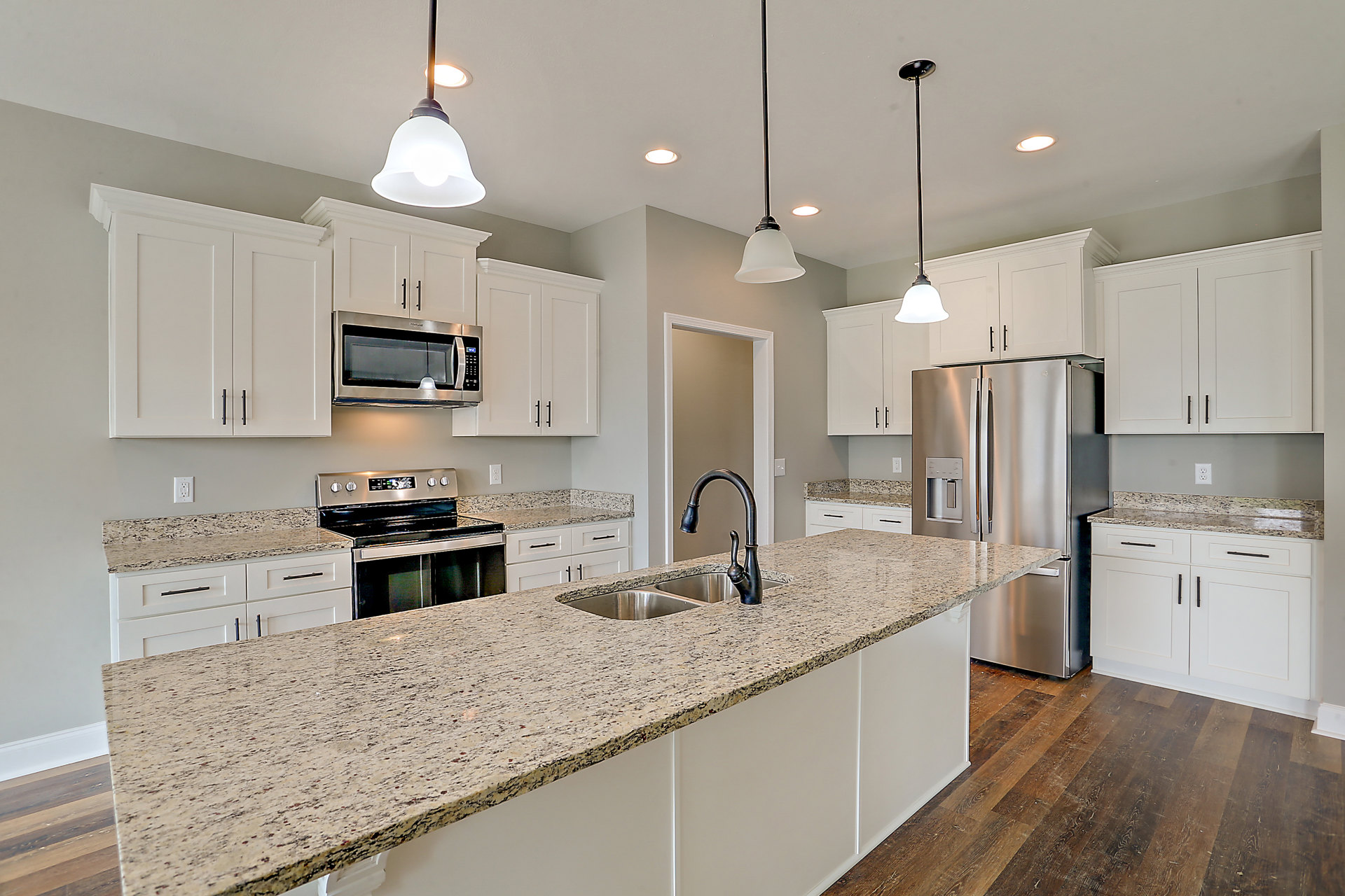 Granite countertops, stainless steel refrigerator and stove, built-in microwave, white cabinetry, undermount sink, and neutral tile backsplash in a modern kitchen