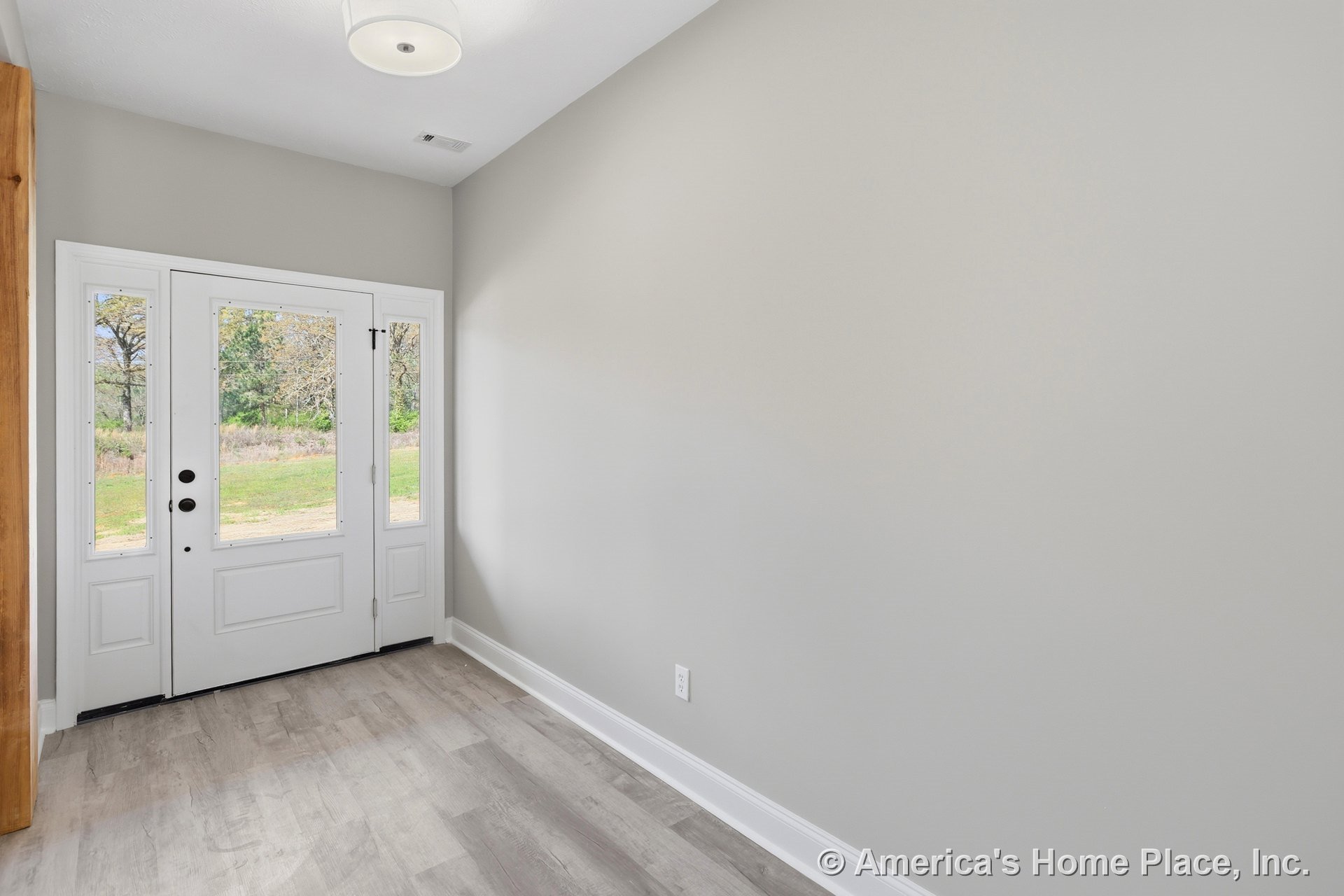 Room with wood flooring, white walls, ceiling fan, and two doors—one solid white and one with glass panels.