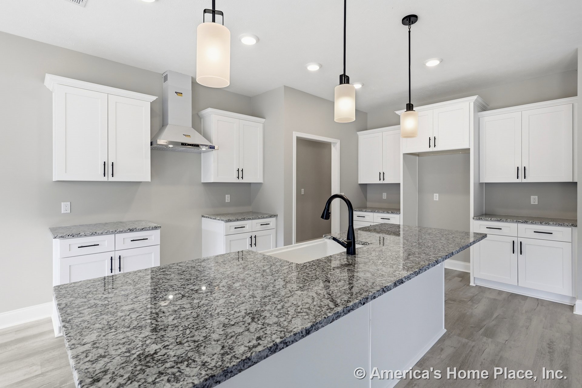 Granite kitchen countertop with undermount sink, black faucet, white cabinetry, stainless steel appliance, and pendant light fixture