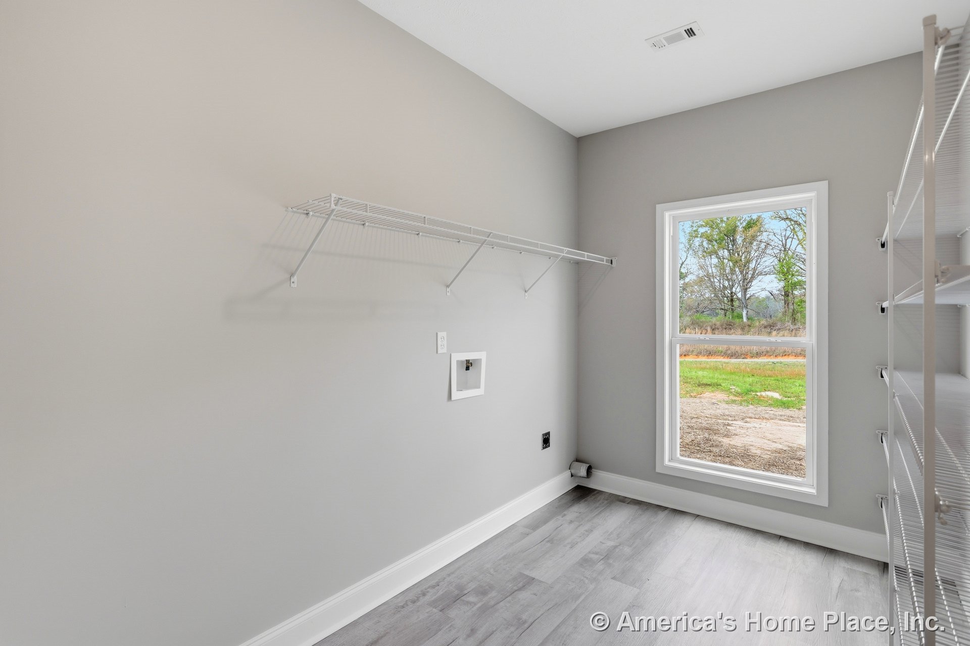 Bright room with white plaster walls, large window overlooking trees, and a simple white wall-mounted rack