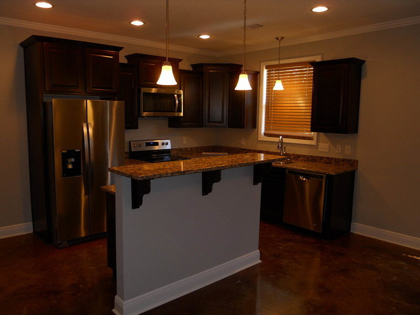 Kitchen featuring stainless steel refrigerator with ice and water dispenser, matching stainless steel appliances, marble countertop island, white cabinetry, and overhead lighting