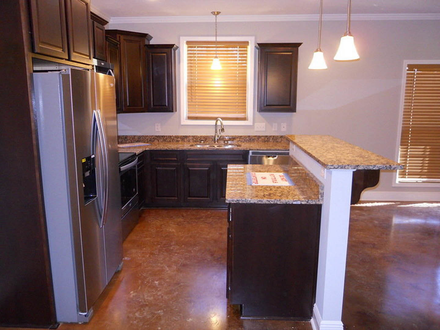 Dark wood kitchen cabinets, granite countertops, stainless steel refrigerator, chrome faucet, ceiling light fixture, window blinds