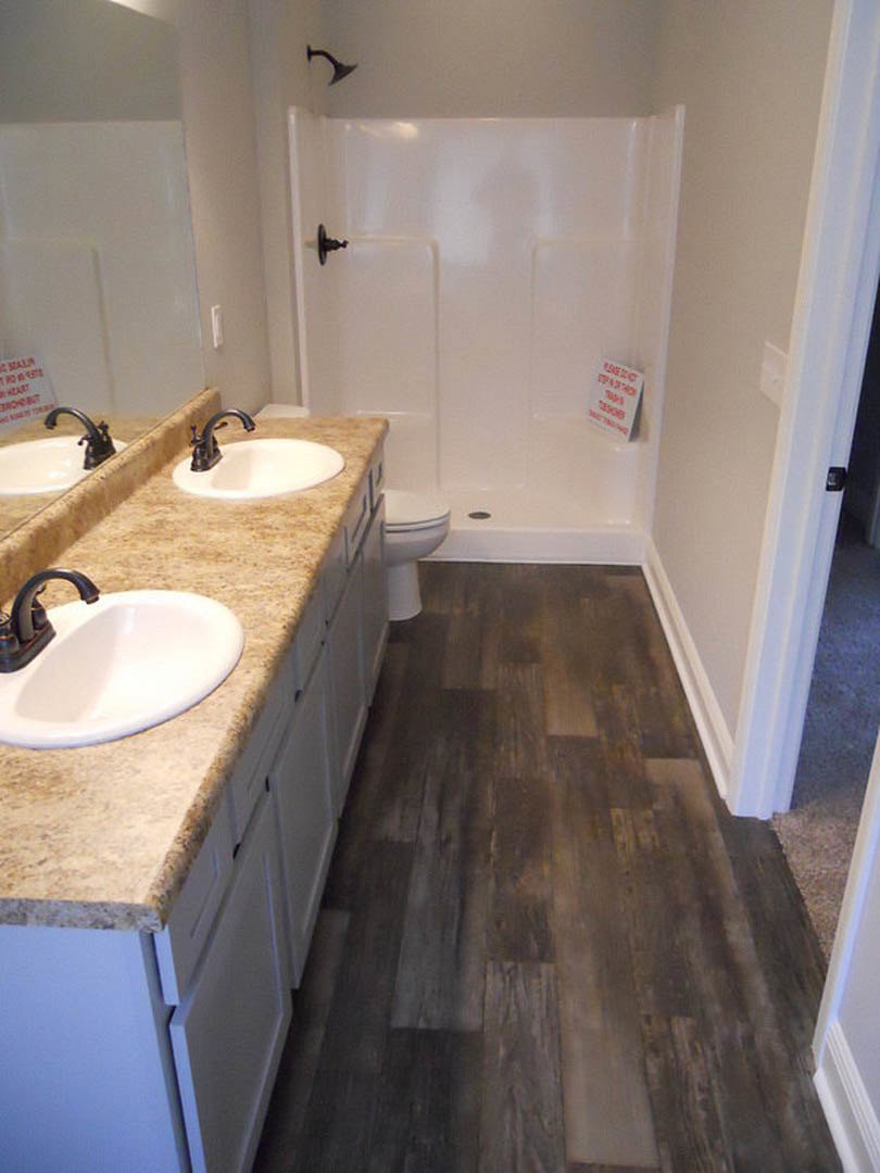 Modern bathroom featuring a glass-enclosed shower, white ceramic sink with chrome faucet, tiled walls and floor, and minimalist countertop accessories