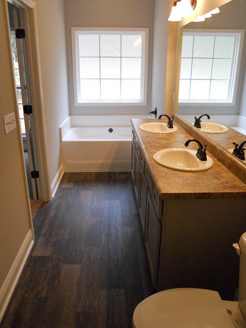 Bathroom with marble countertop sink, freestanding bathtub, tiled floor and walls, chrome plumbing fixtures, and large window providing natural light