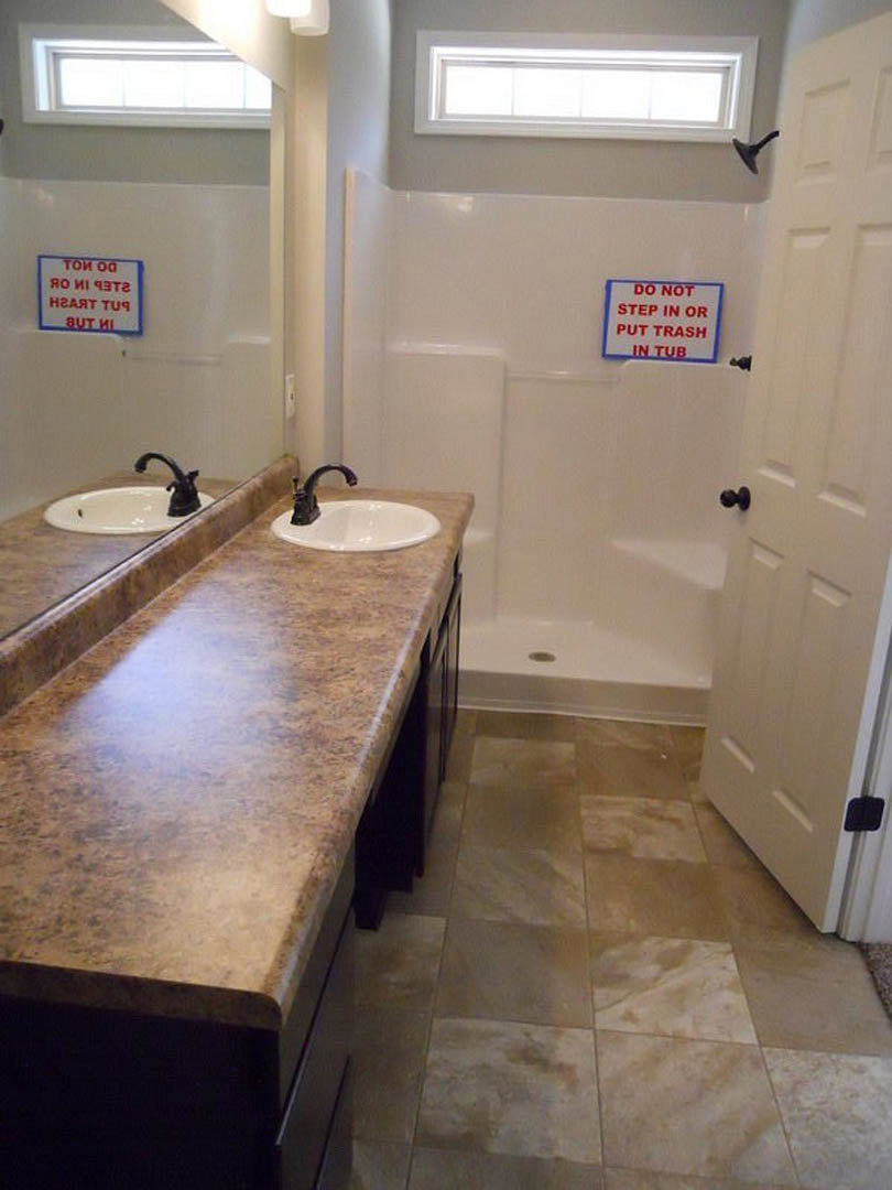Bathroom featuring marble countertop with dual sinks, glass-enclosed shower, tile flooring, chrome fixtures, and neutral wall finishes