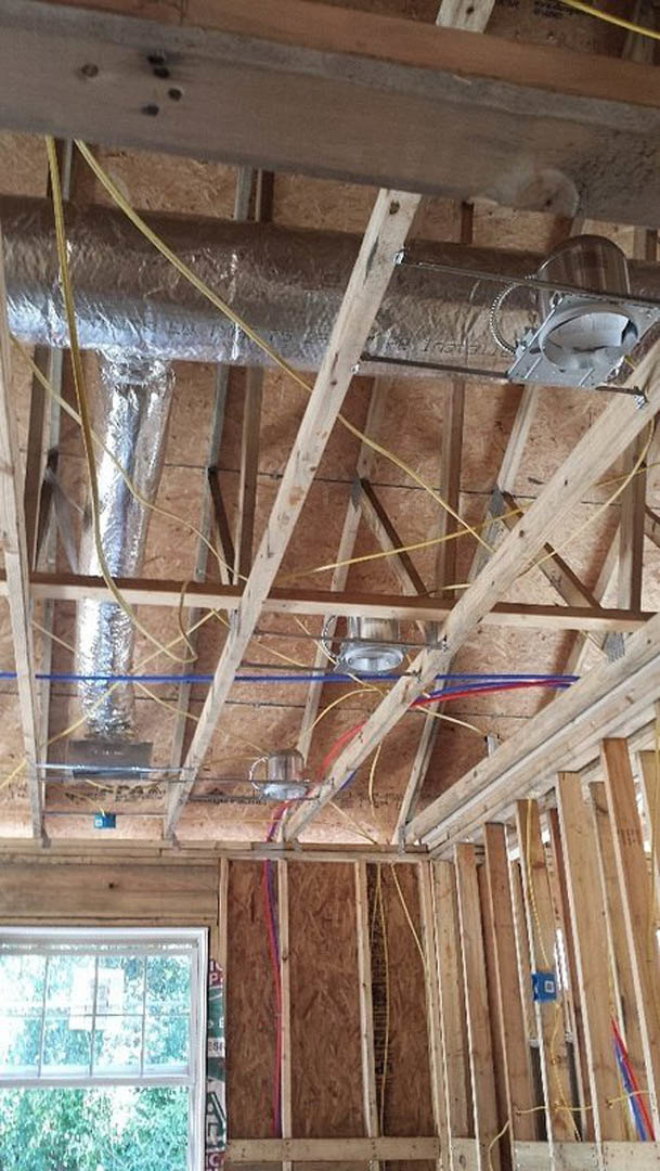 Exposed wood beams and metal ductwork running across unfinished ceiling with visible insulation