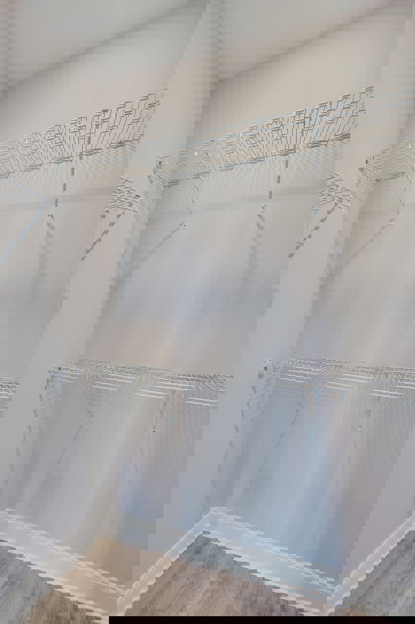 White built-in shelves against a white plaster wall, wood floor and baseboard trim, white ceiling, minimalist interior design.