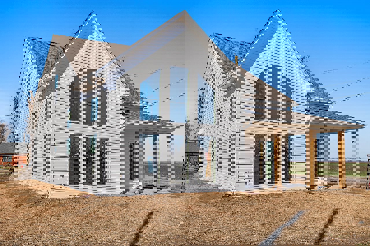 Large front porch with white columns, red metal roof, blue windows with white trim, siding exterior, window reflecting trees, blue container visible in window