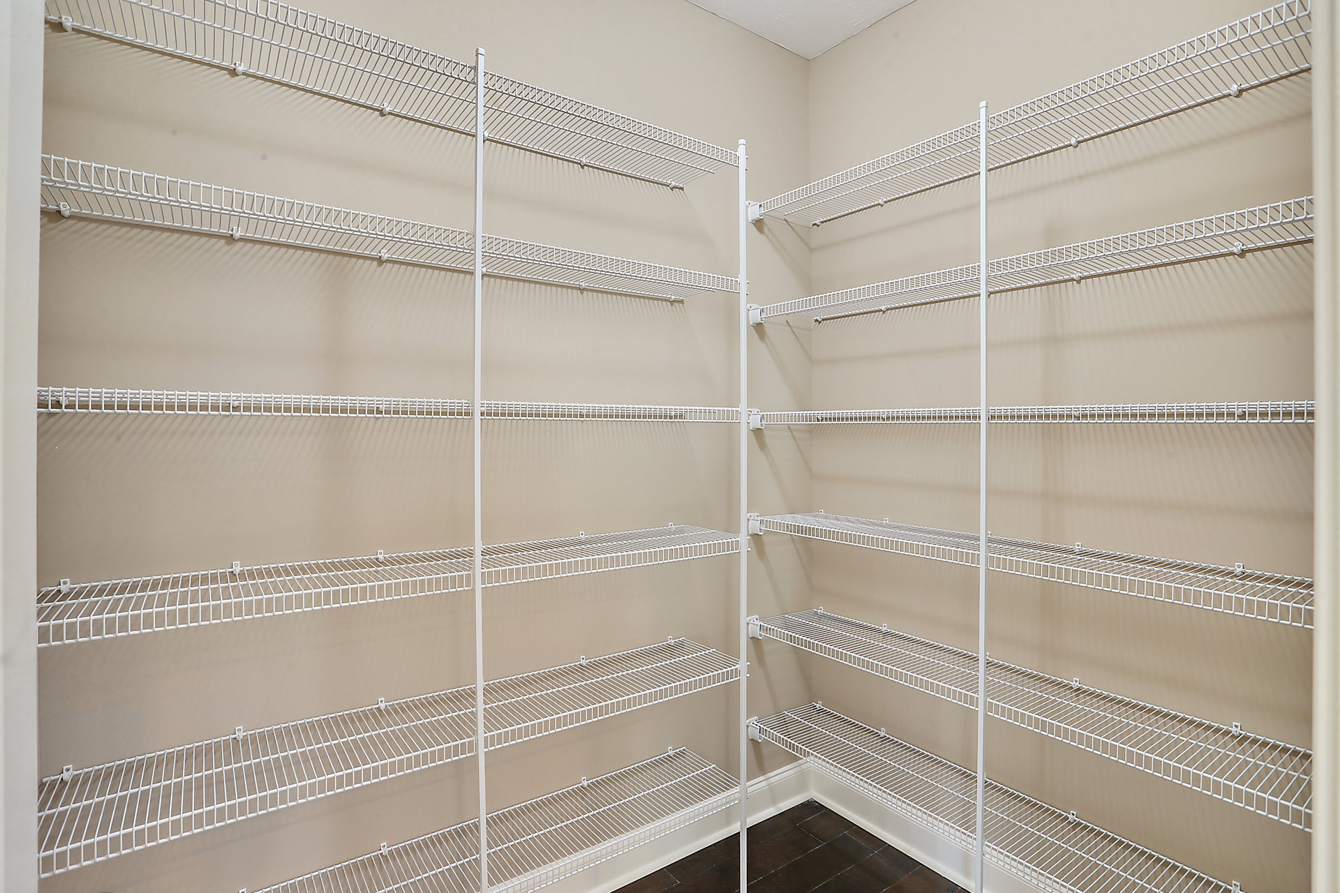 White wire shelving mounted on a wall in a room with light-colored walls and ceiling