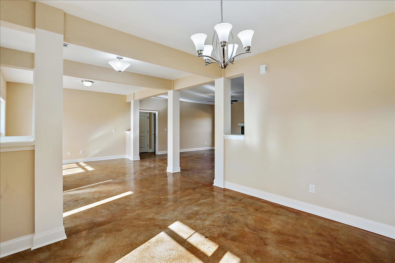 Open hallway with white door, brown laminate flooring, plaster walls, ceiling molding, and modern ceiling fixture with five lights.