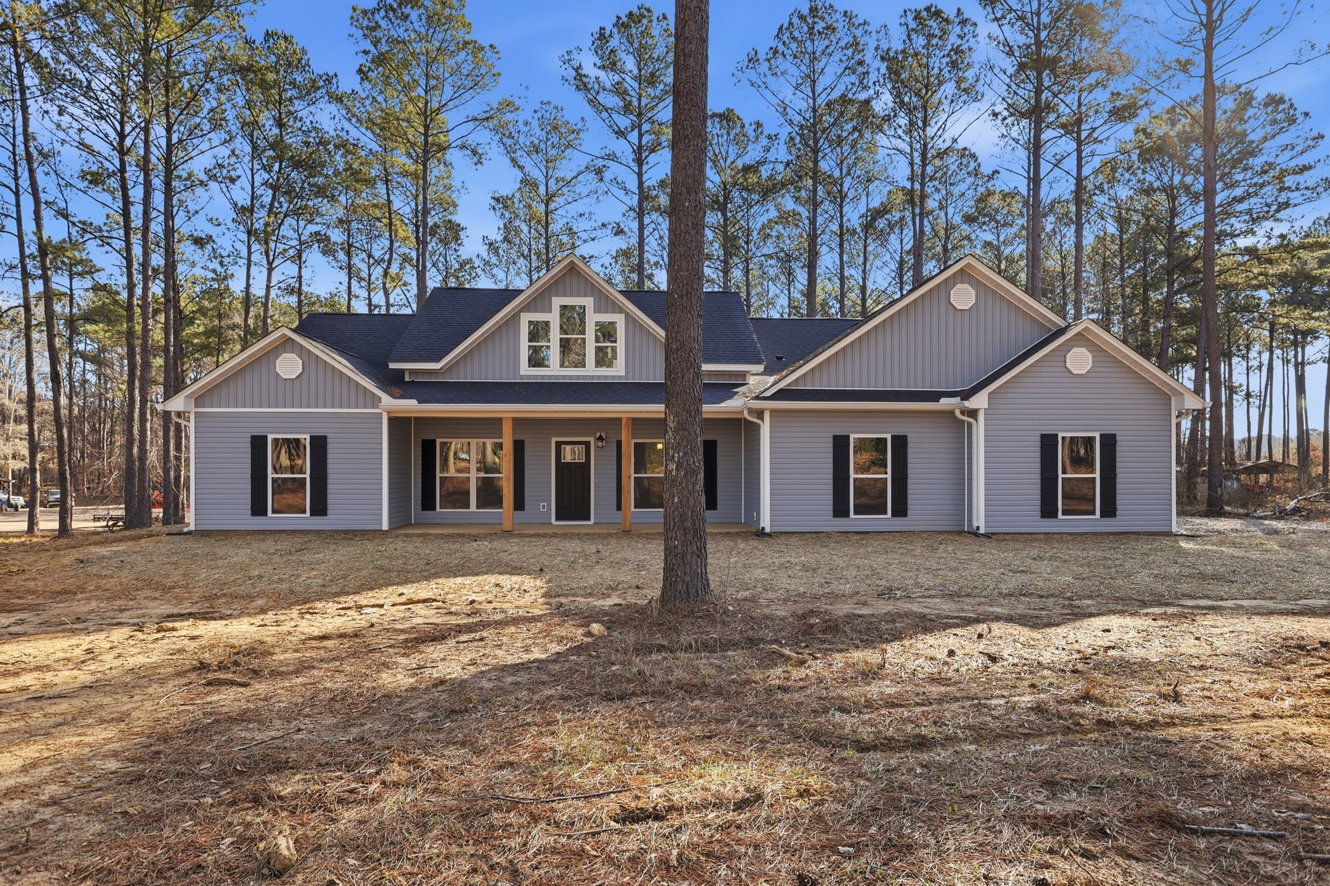 White siding house with black front door and window, large tree in front yard, trees reflected in windows, Little White House visible in background.