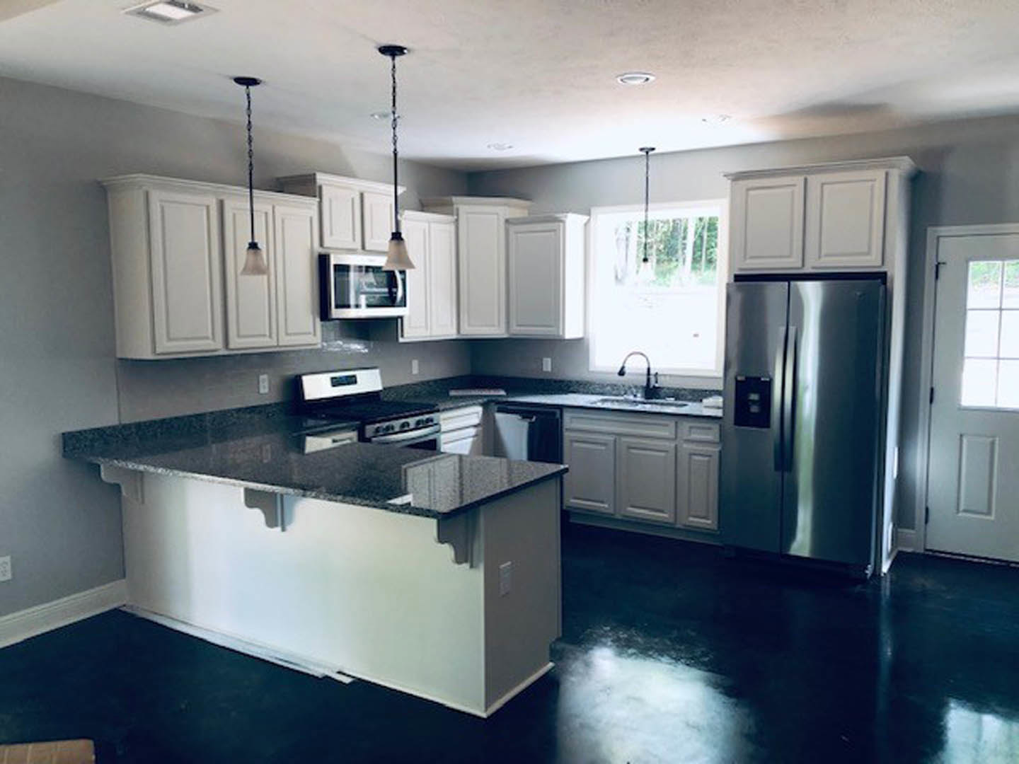 Modern kitchen featuring glossy black tile flooring, white shaker cabinets, stainless steel refrigerator, built-in stove, quartz countertops, undermount sink, and recessed