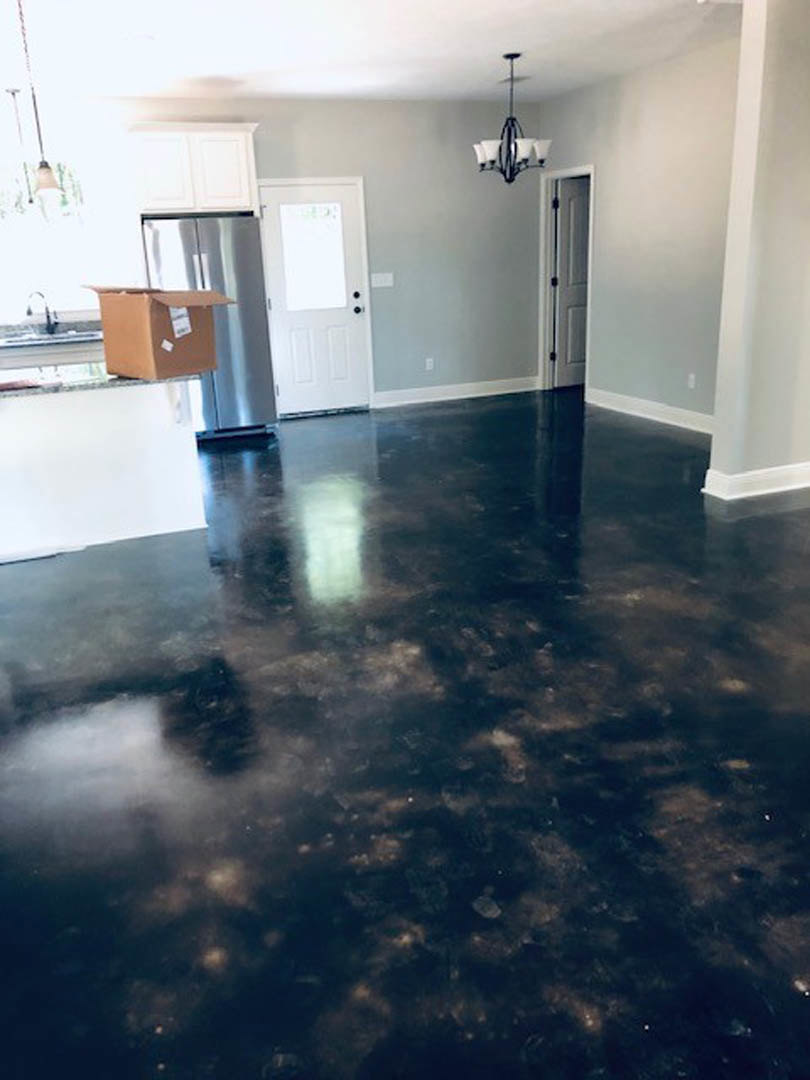Black glossy tile floor with white walls, white door featuring a white panel, brown box with white label, and close-up view of a chandelier in a modern kitchen interior.