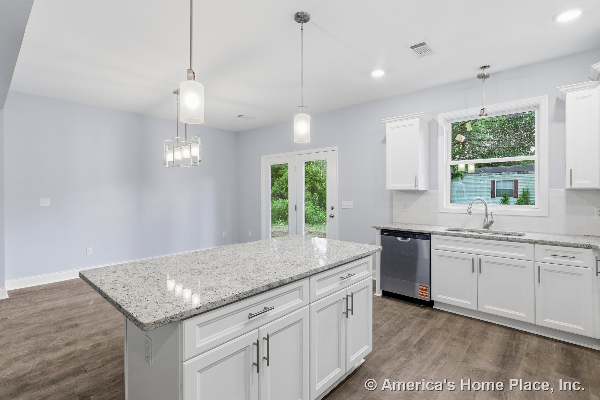 White kitchen with granite countertops, large central island, stainless steel appliances, pendant lighting, subway tile backsplash, wide window above sink, double glass patio