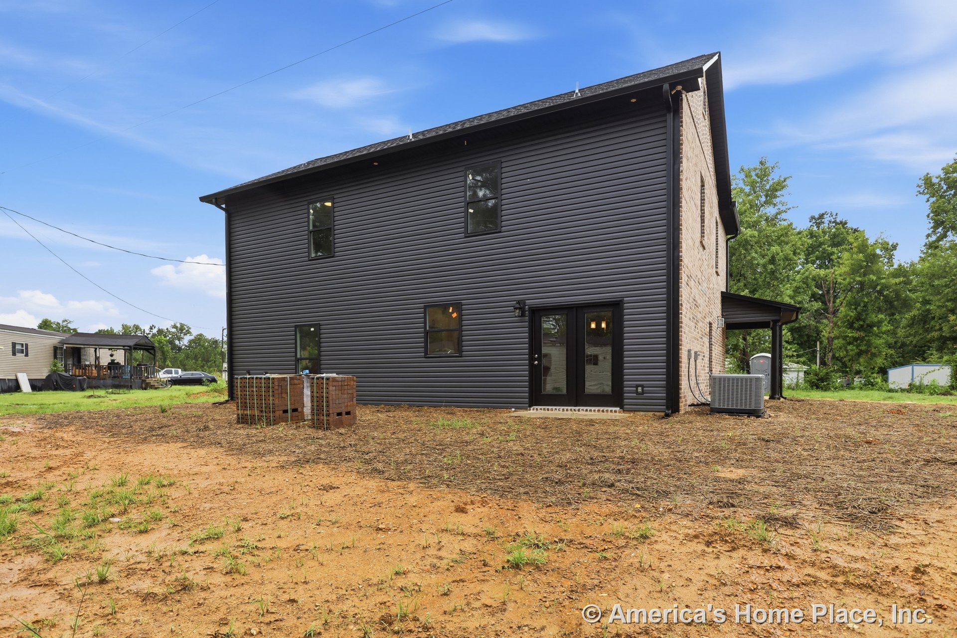 Dark horizontal siding with brick accent wall, multiple rectangular windows, double glass exterior doors, covered porch area, central air conditioning unit, modern trim, outdoor