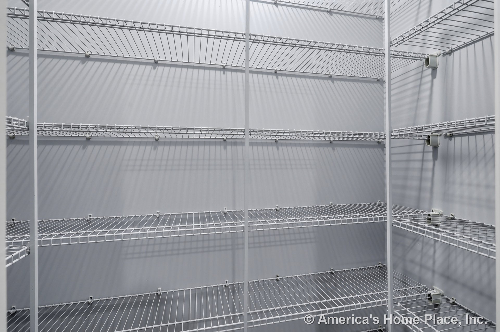 Built-in pantry with multiple wall-mounted white wire shelving units, vertical support bars, open shelving design, and gray painted walls.