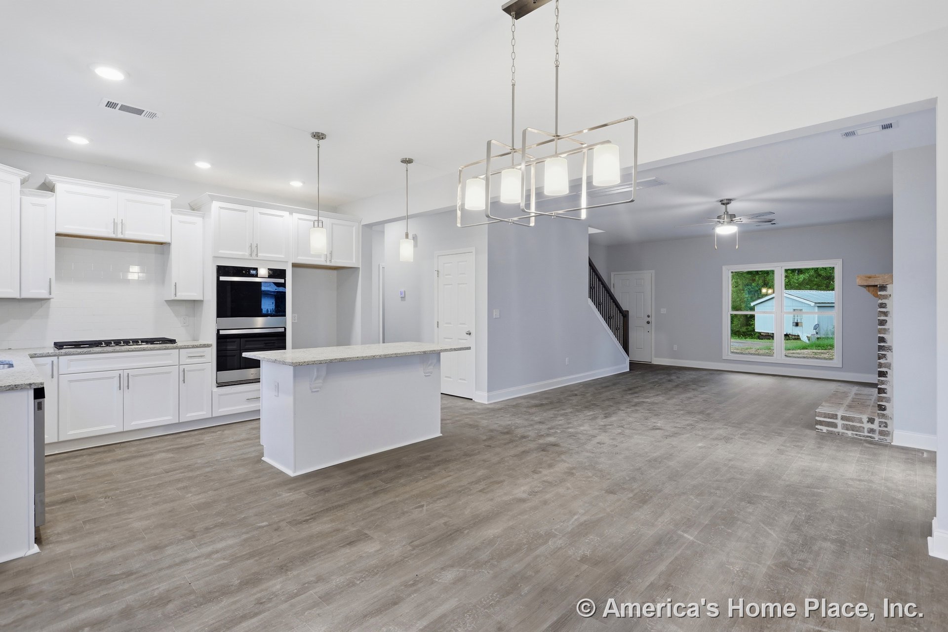 Open-concept kitchen and living area with white shaker cabinets, granite island, double wall oven, modern pendant lights, wood-look flooring, recessed lighting, large living room