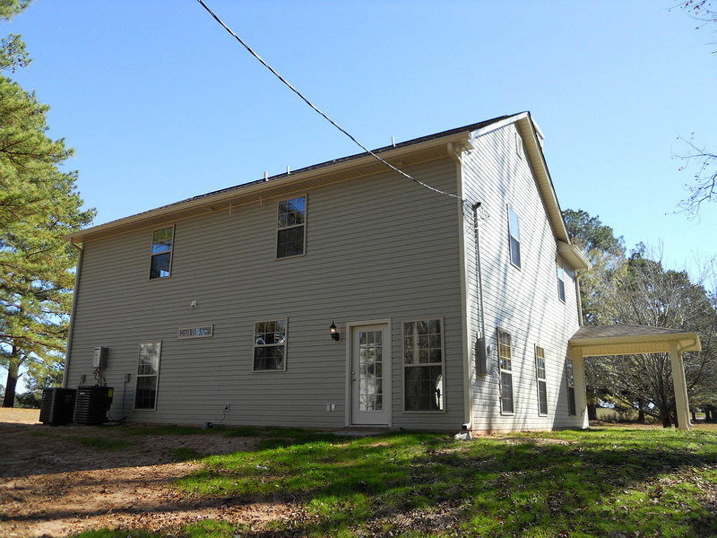 White house with multi-pane windows, covered front porch, green lawn, and overhead power line.