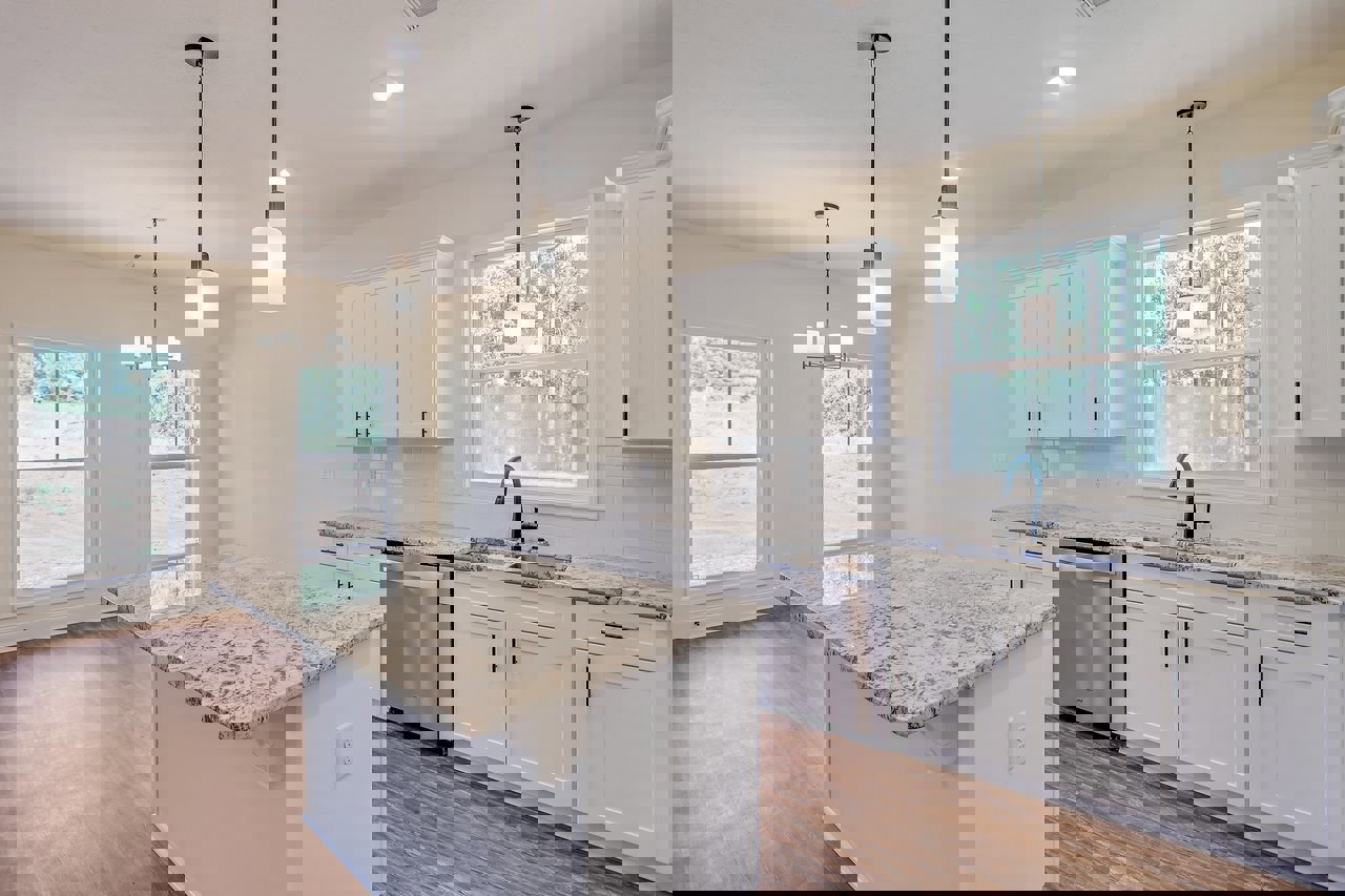 Marble kitchen countertop with stainless steel dishwasher, white cabinetry, overhead ceiling light, window overlooking grassy field