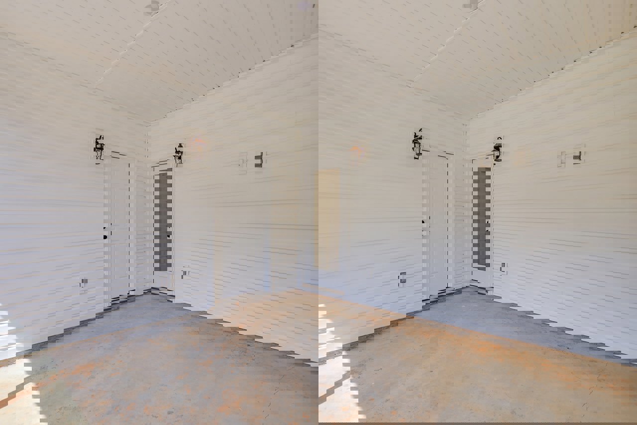 White interior with two white doors featuring black knobs, smooth plaster walls, concrete flooring, and a white ceiling with recessed lighting.