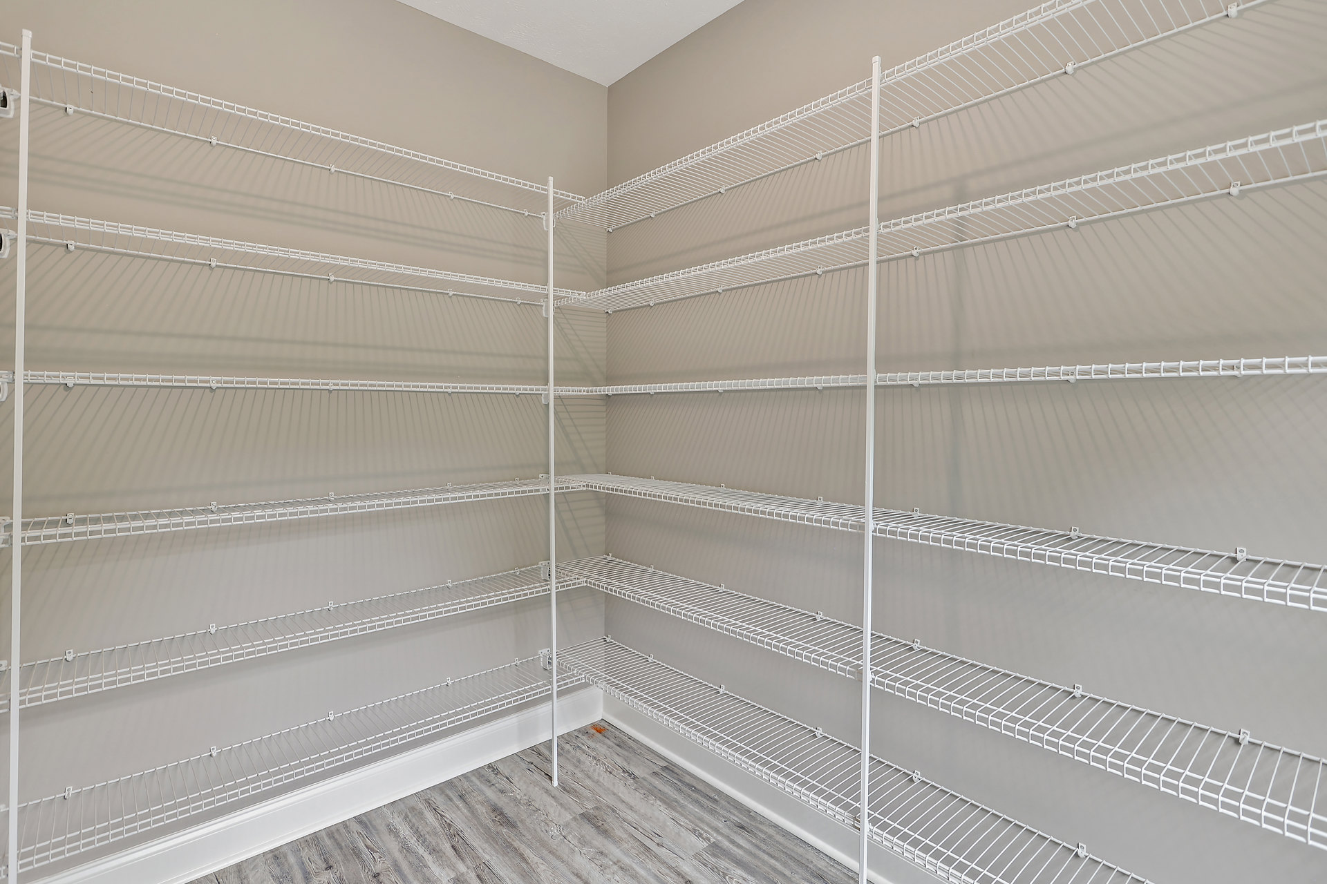 Empty closet with white metal shelving, carpeted floor, and window.