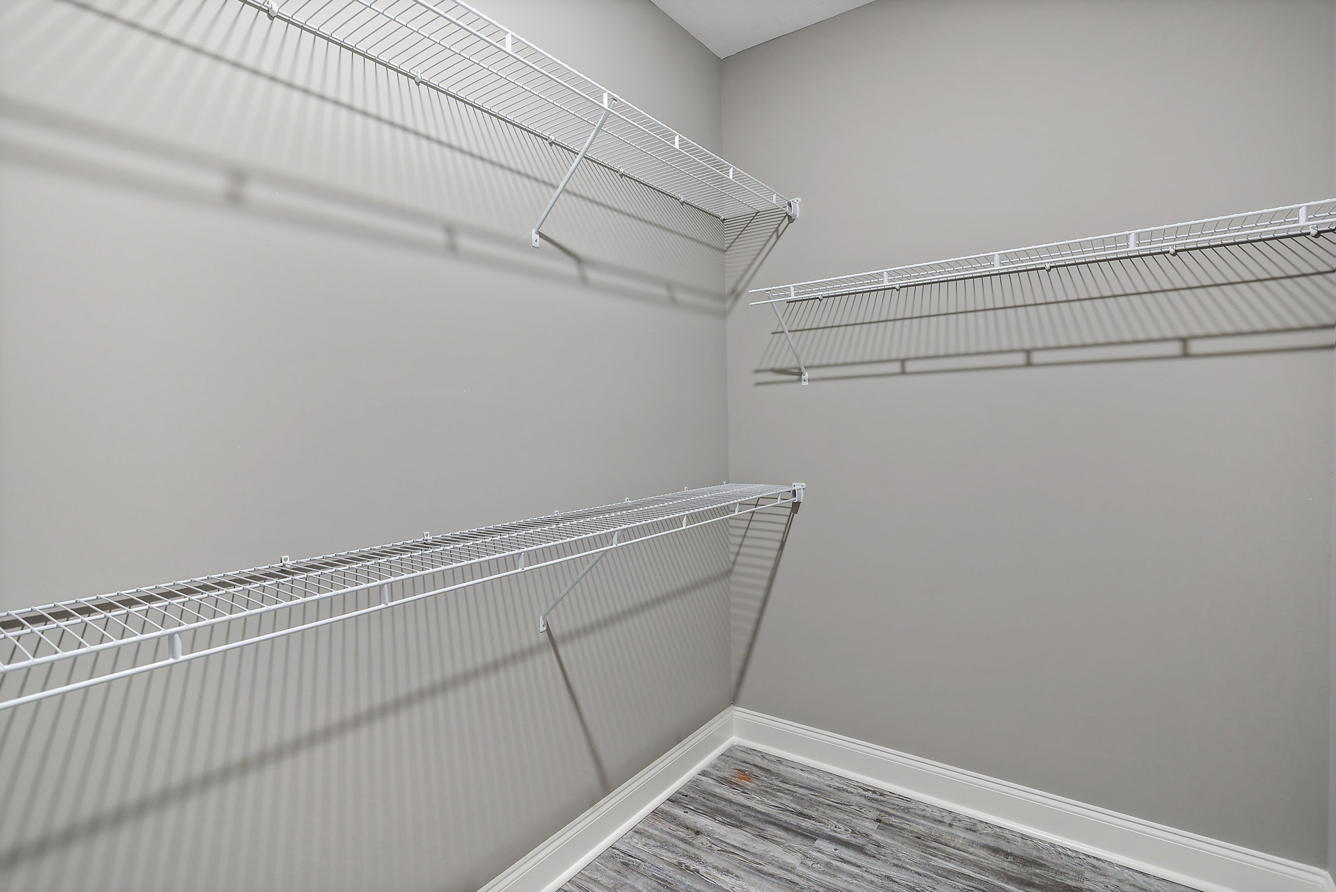 Built-in white shelving along a plaster wall, beige carpet flooring, wood trim, and recessed ceiling in a residential interior room.
