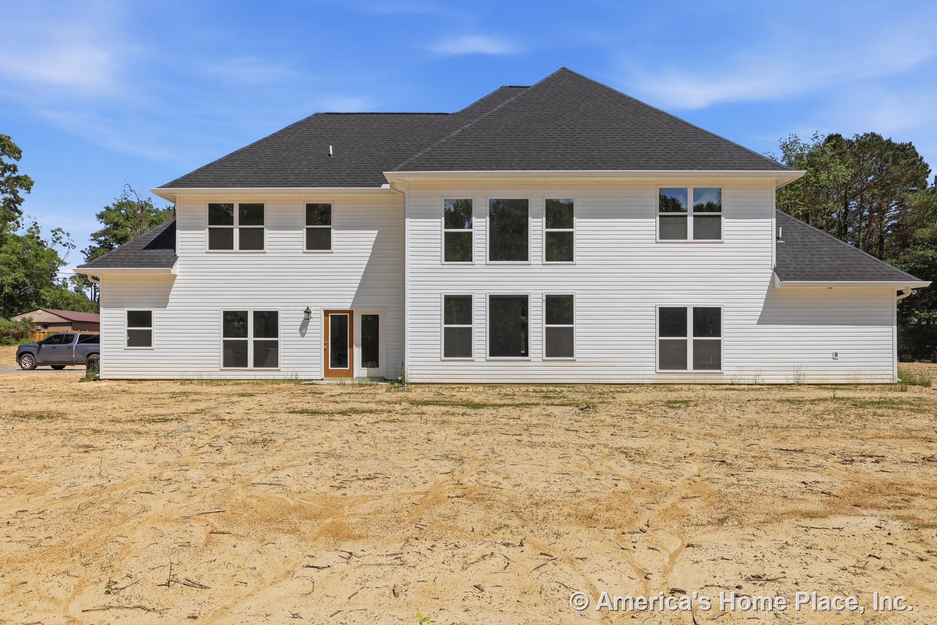 Two-story modern home with white vinyl horizontal siding, dark asphalt shingle roof, multiple large rectangular windows, glass exterior door, and outdoor wall-mounted light