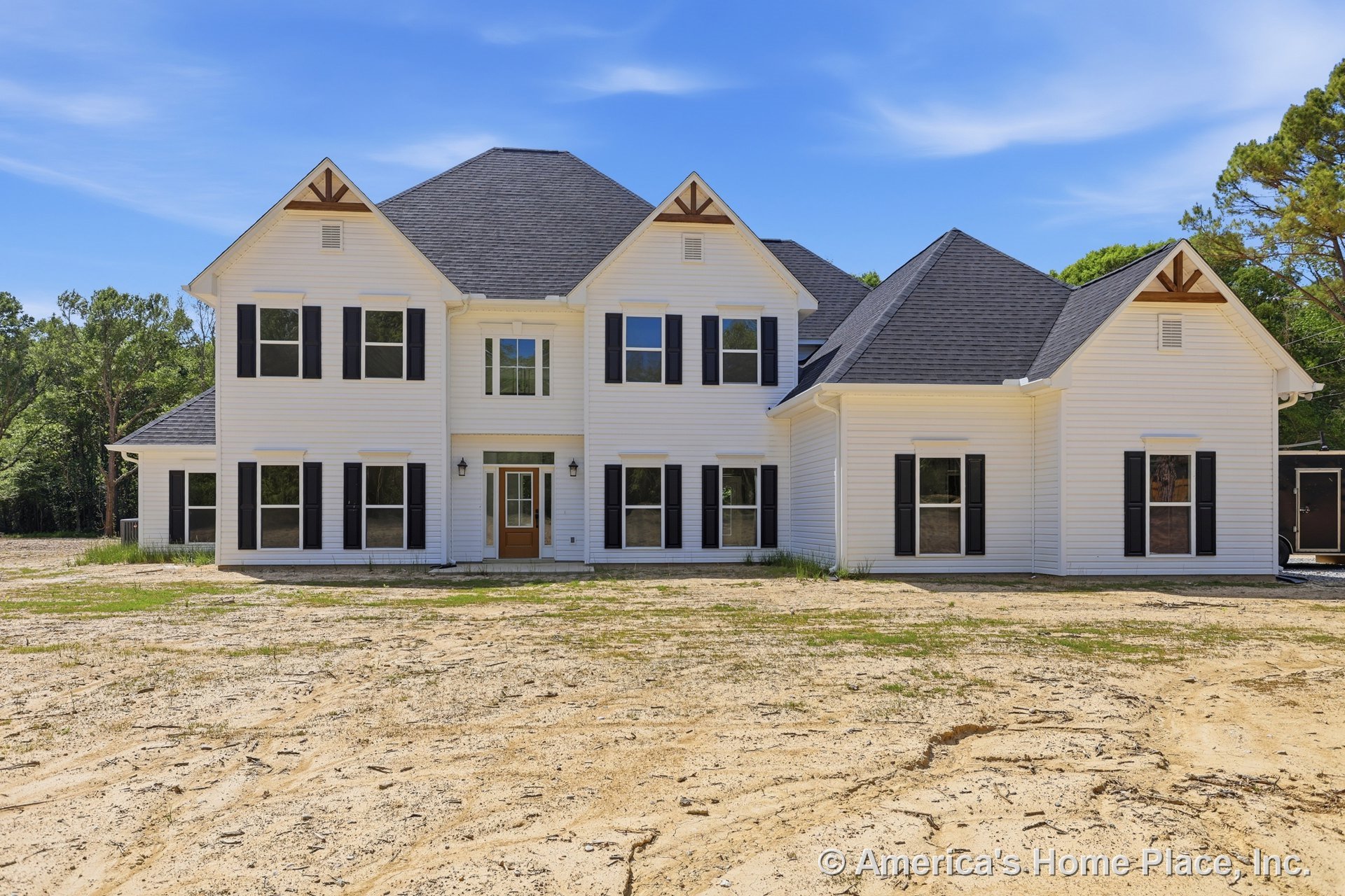 Two-story home with white horizontal siding, black window shutters, decorative gable trim, multi-pane windows, covered entry with sidelights, and dark shingle roof.