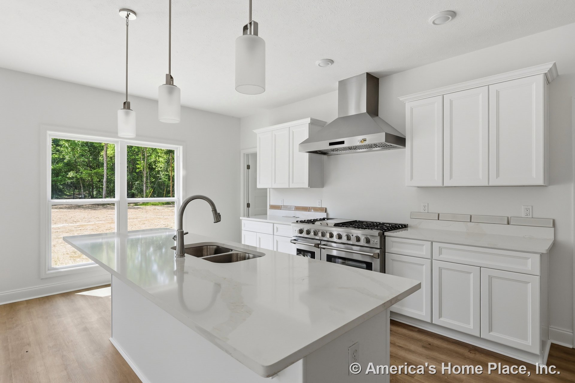 White shaker cabinets and full-height upper cabinetry surround a spacious kitchen with a large quartz island featuring an undermount sink and pendant lighting. Stainless steel