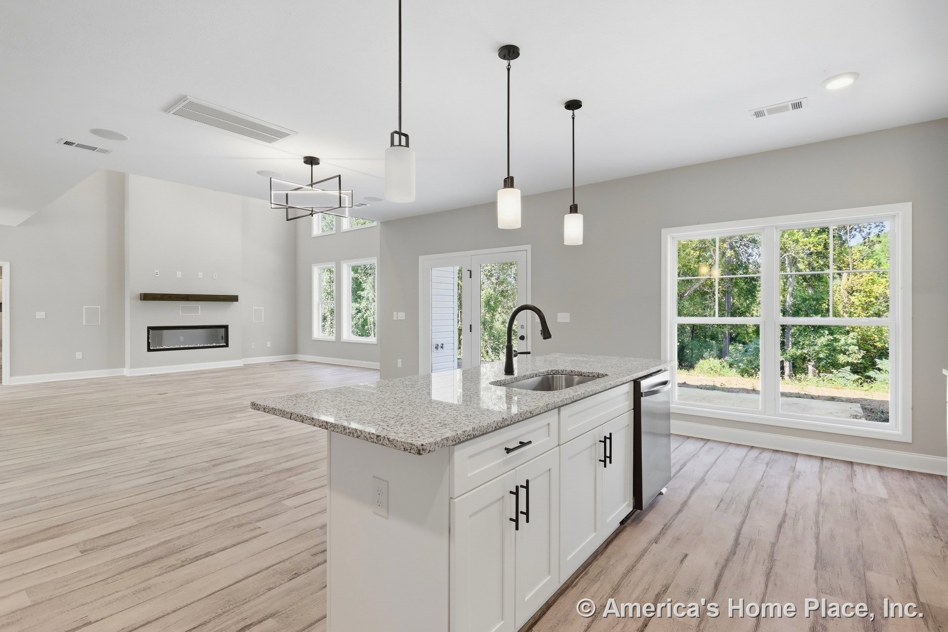 Open concept kitchen and living area with large granite island, white shaker cabinets, pendant lighting, expansive picture windows, light wood flooring, modern linear fireplace