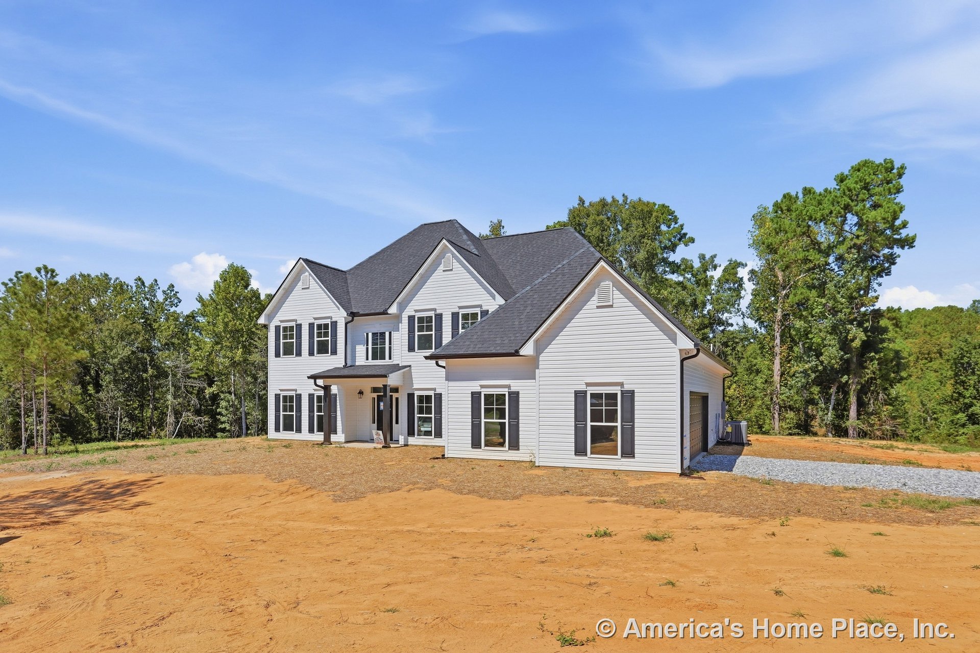 Two-story exterior with white horizontal siding, black roof shingles, covered front porch, multiple double-hung windows with black shutters, attached garage, and paved driveway.