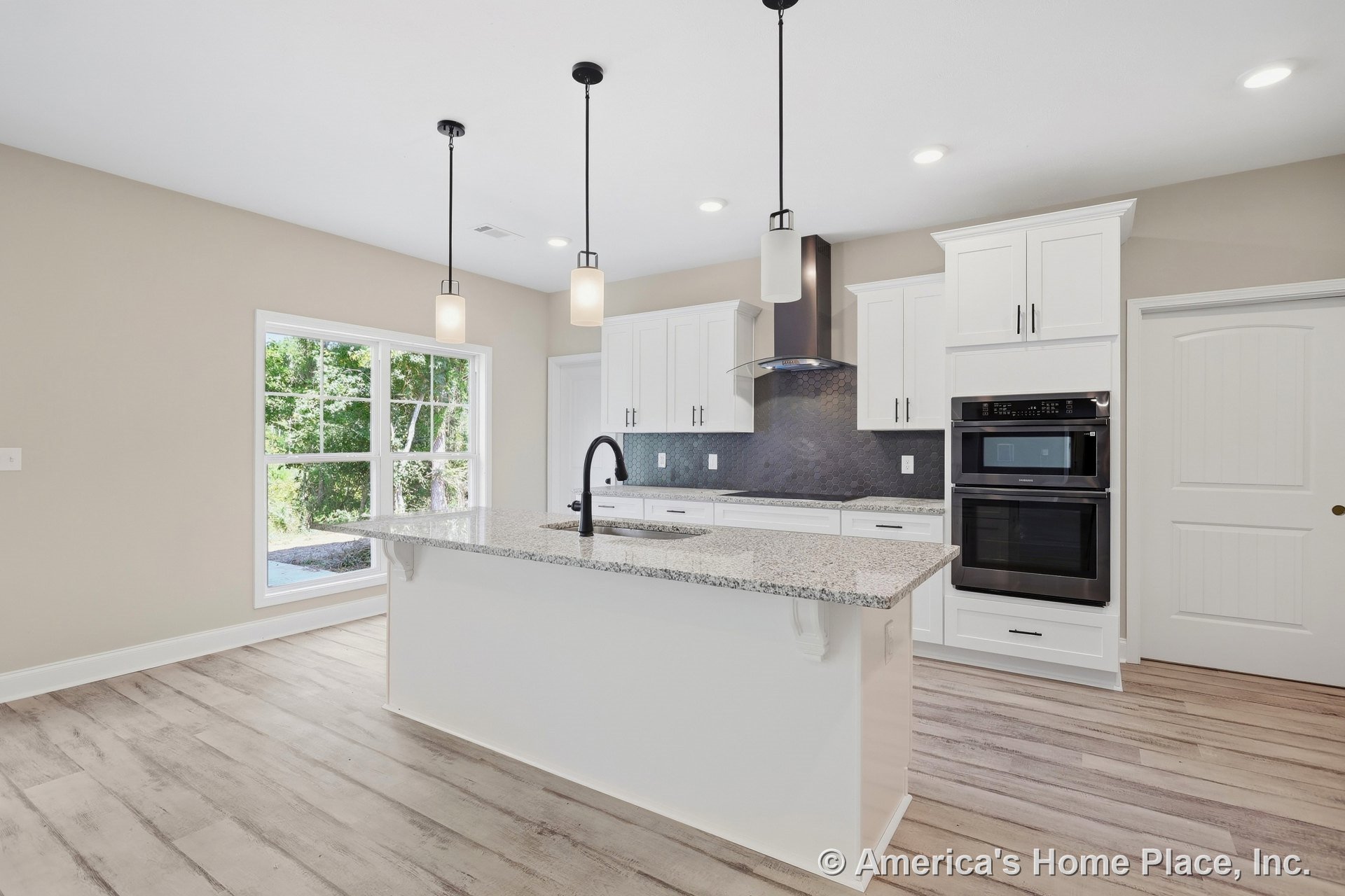 Spacious kitchen with large granite island, white shaker cabinets, black hexagonal tile backsplash, double wall ovens, pendant lights, wide plank wood-look flooring, and built-in