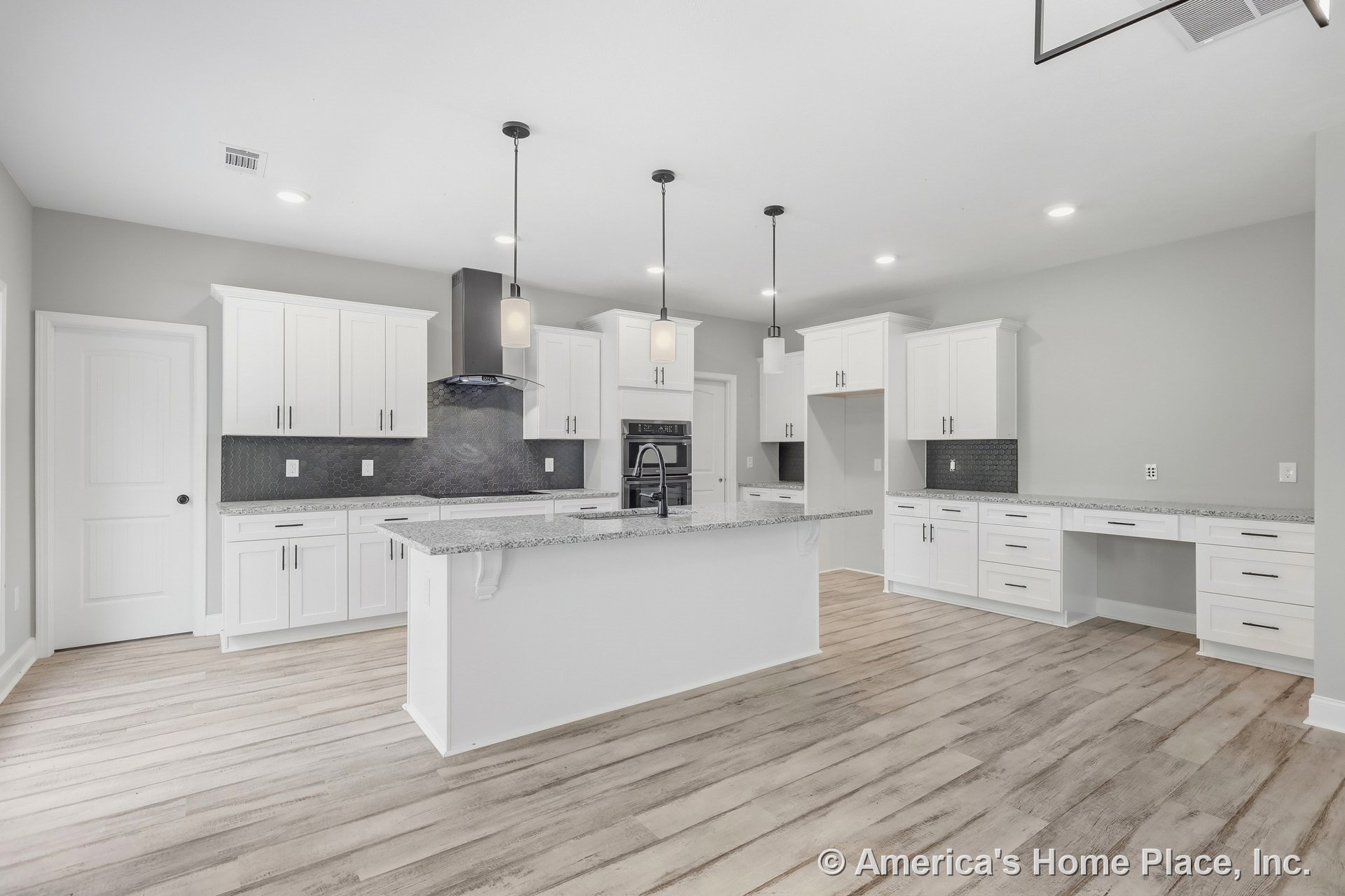 White shaker cabinets, granite countertops, hexagonal tile backsplash, large central kitchen island with pendant lights, wood-look plank flooring, built-in oven, open layout
