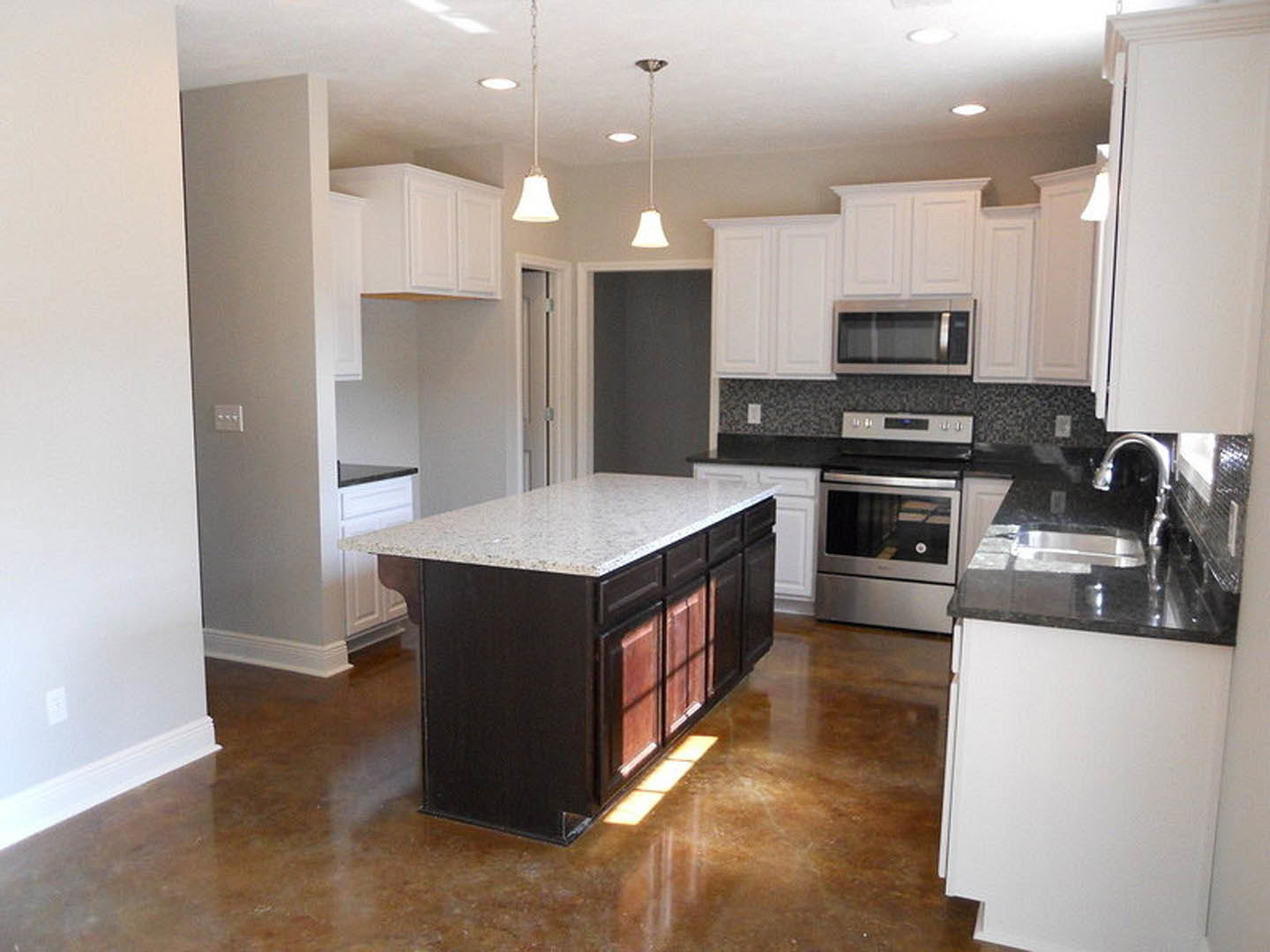 White kitchen with shaker cabinets, marble island countertop, stainless steel appliances, pendant lighting, and hardwood floors