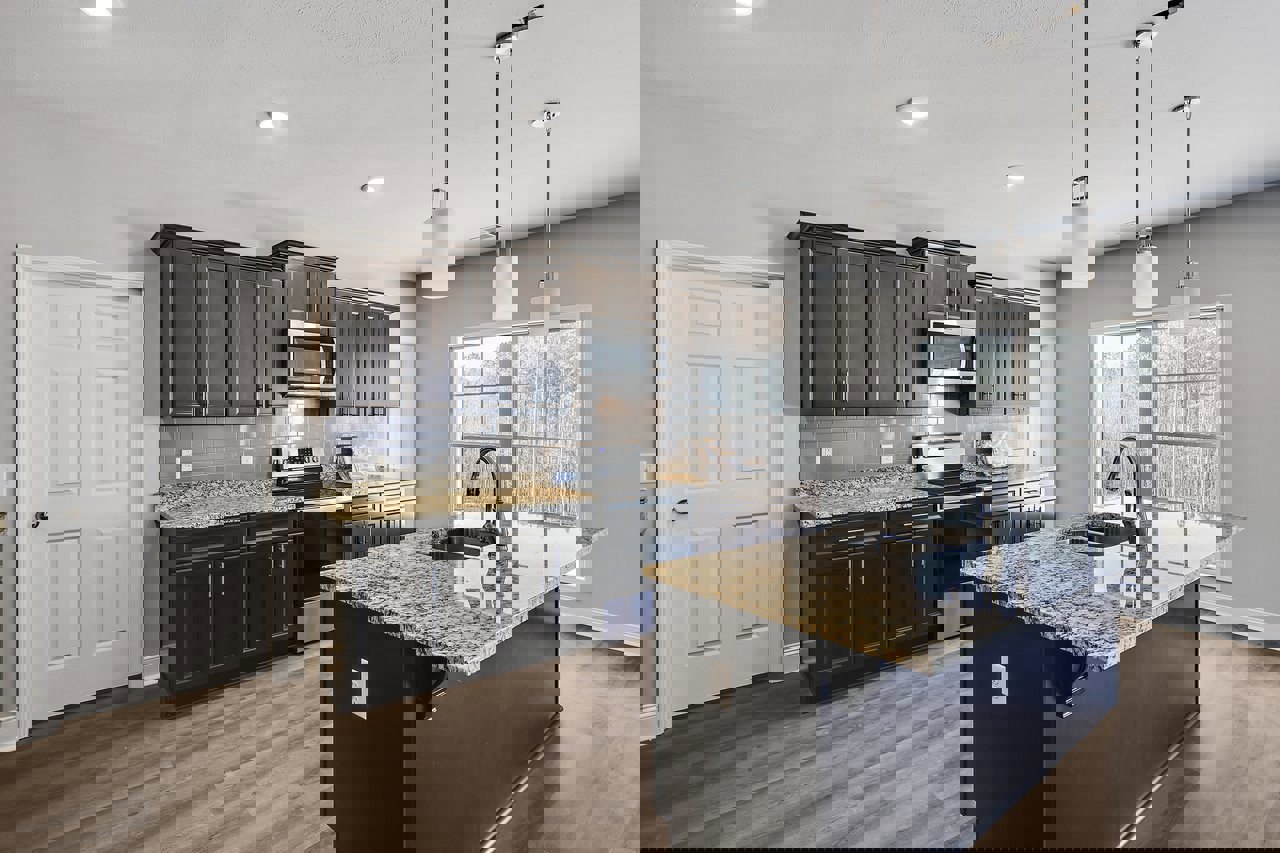 Granite kitchen island with built-in sink, stainless steel stove, white cabinetry, tile backsplash, microwave, and windows providing natural light