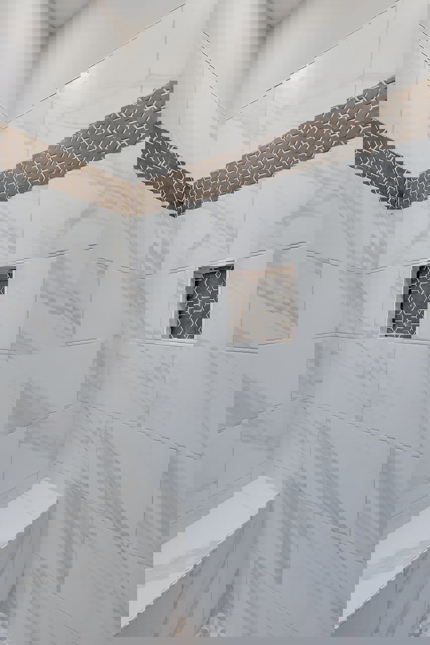 White tile shower featuring a recessed square niche in the wall, white border tiles, and a subtle black stripe accent.