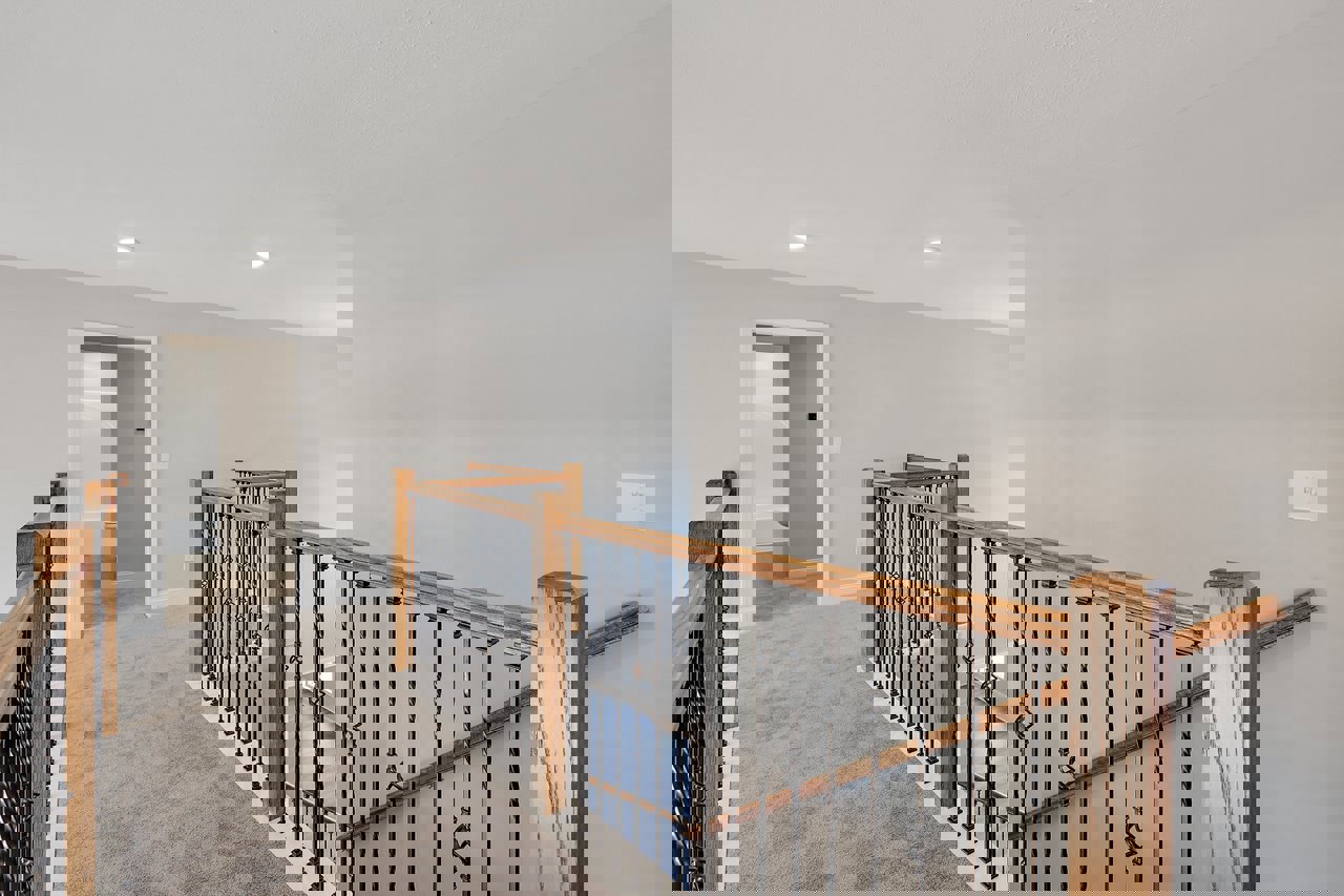 Wood staircase with metal railings, white door, plaster walls, light switch, and wall-mounted light fixture in a residential interior