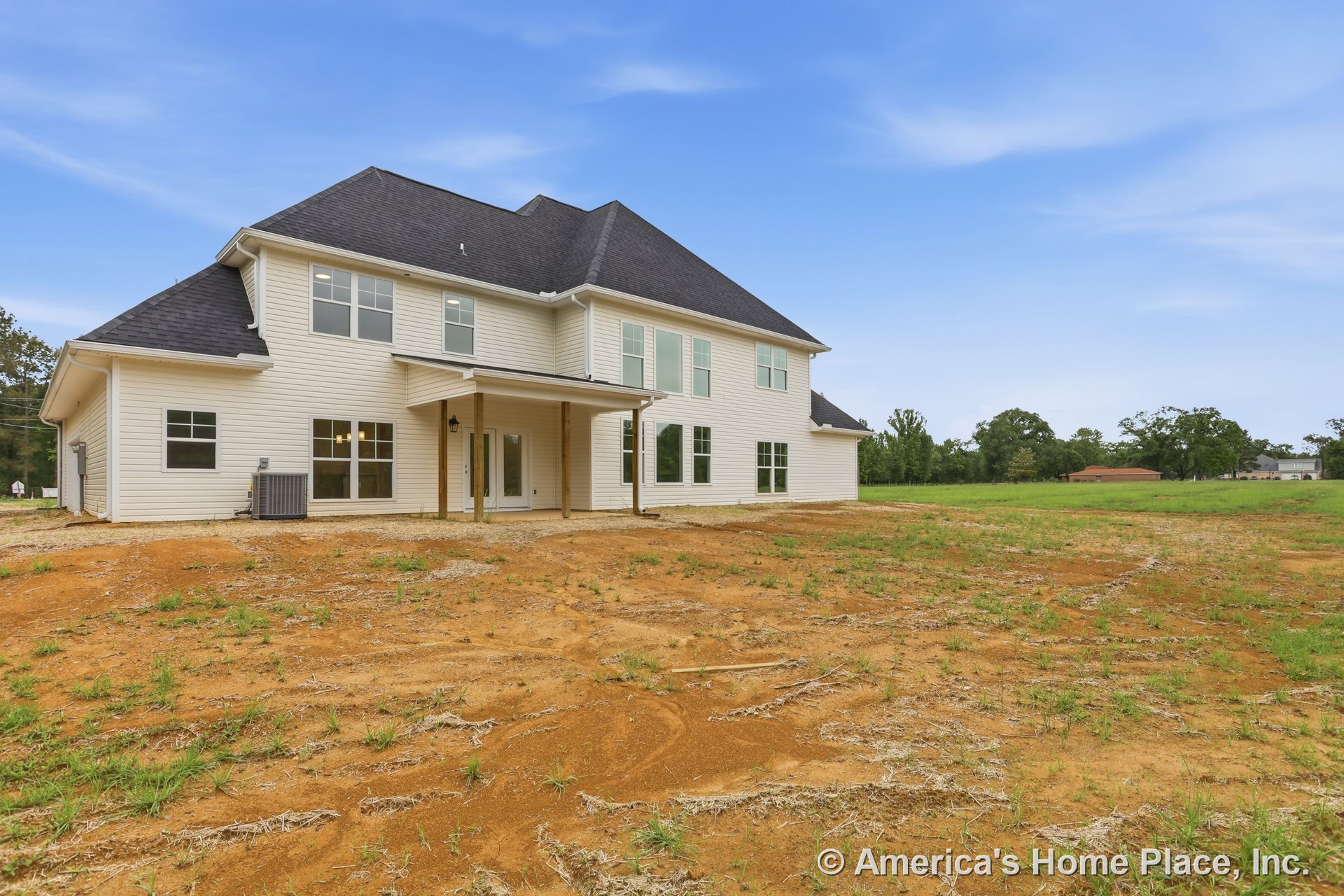 Two-story home with light-colored siding, dark shingle roof, multiple double-hung windows, covered rear porch supported by columns, exterior lighting fixture near entry door, and