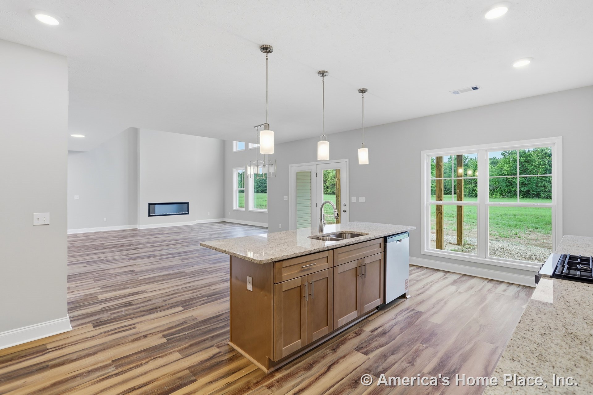 Granite kitchen island with pendant lighting, wood-look flooring, open concept layout connecting kitchen to living area with modern linear fireplace, large windows in dining area