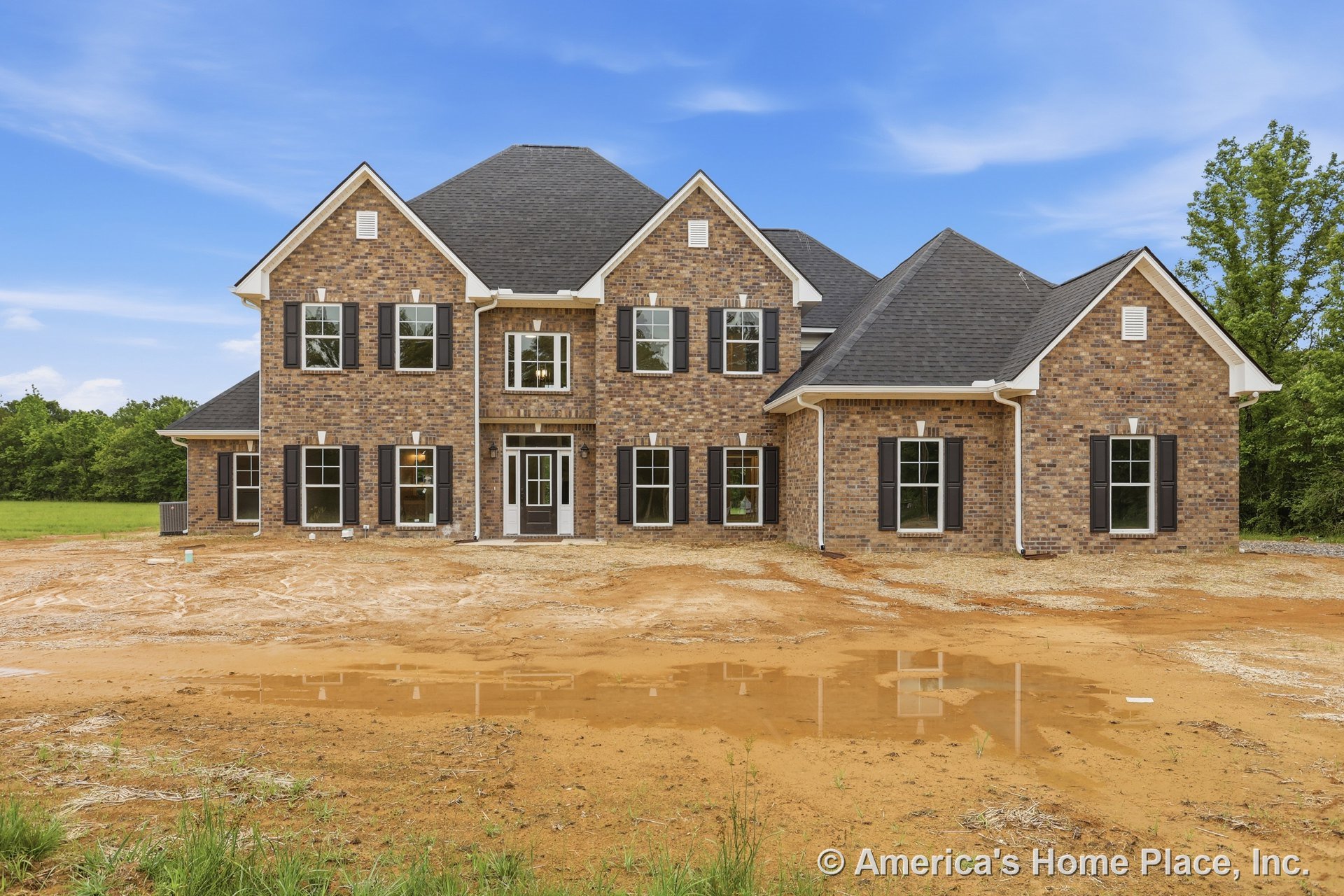 Two-story brick facade with black shutters, multiple double-hung windows, covered entryway, hip roof with asphalt shingles, and white trim accents