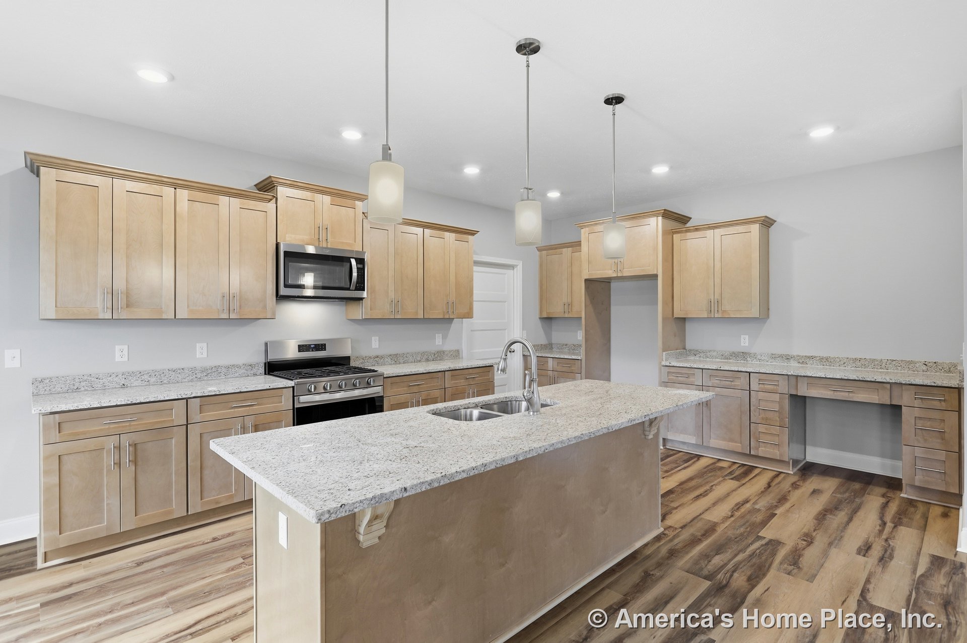 Light wood shaker cabinets and granite countertops, central kitchen island with built-in sink, stainless steel range and microwave, pendant and recessed ceiling lighting, wood-look