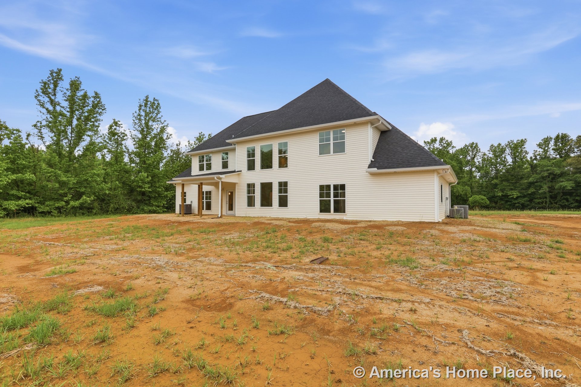 White horizontal siding and black shingle roof on a two-story home with multiple double-hung windows, covered rear porch supported by columns, rear entry door, and unfinished yard.